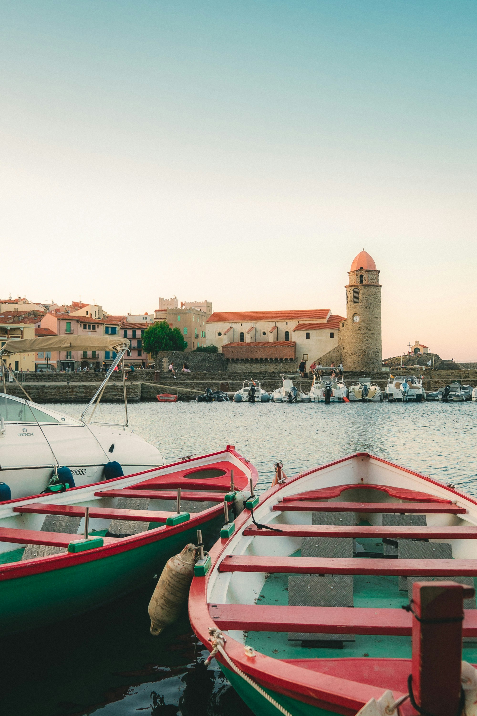 Colorful boats docked in a harbor with town in background