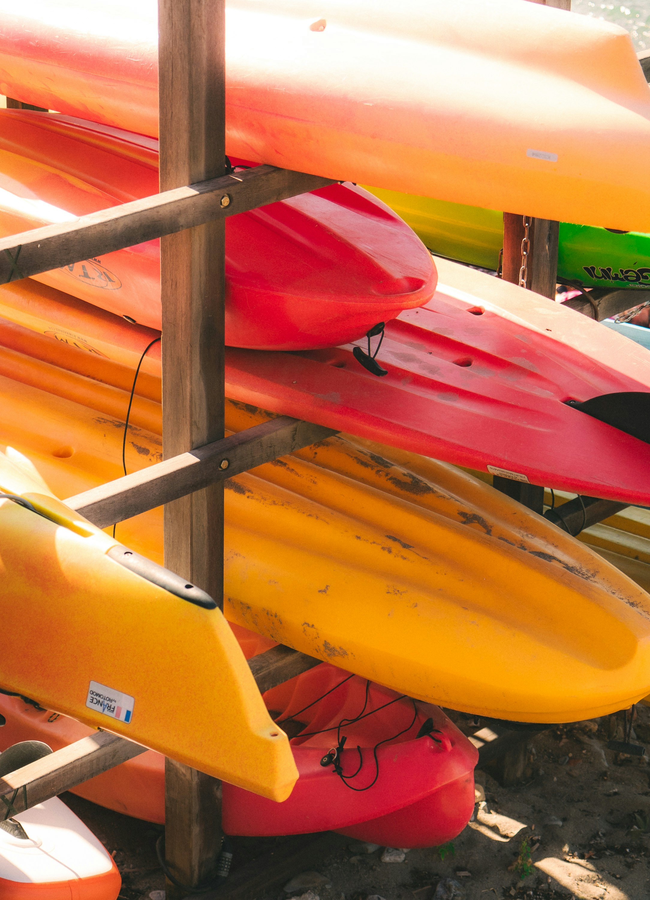 Colorful kayaks stacked on a wooden rack.