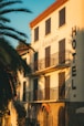 Hotel building with balconies and palm trees at sunset.