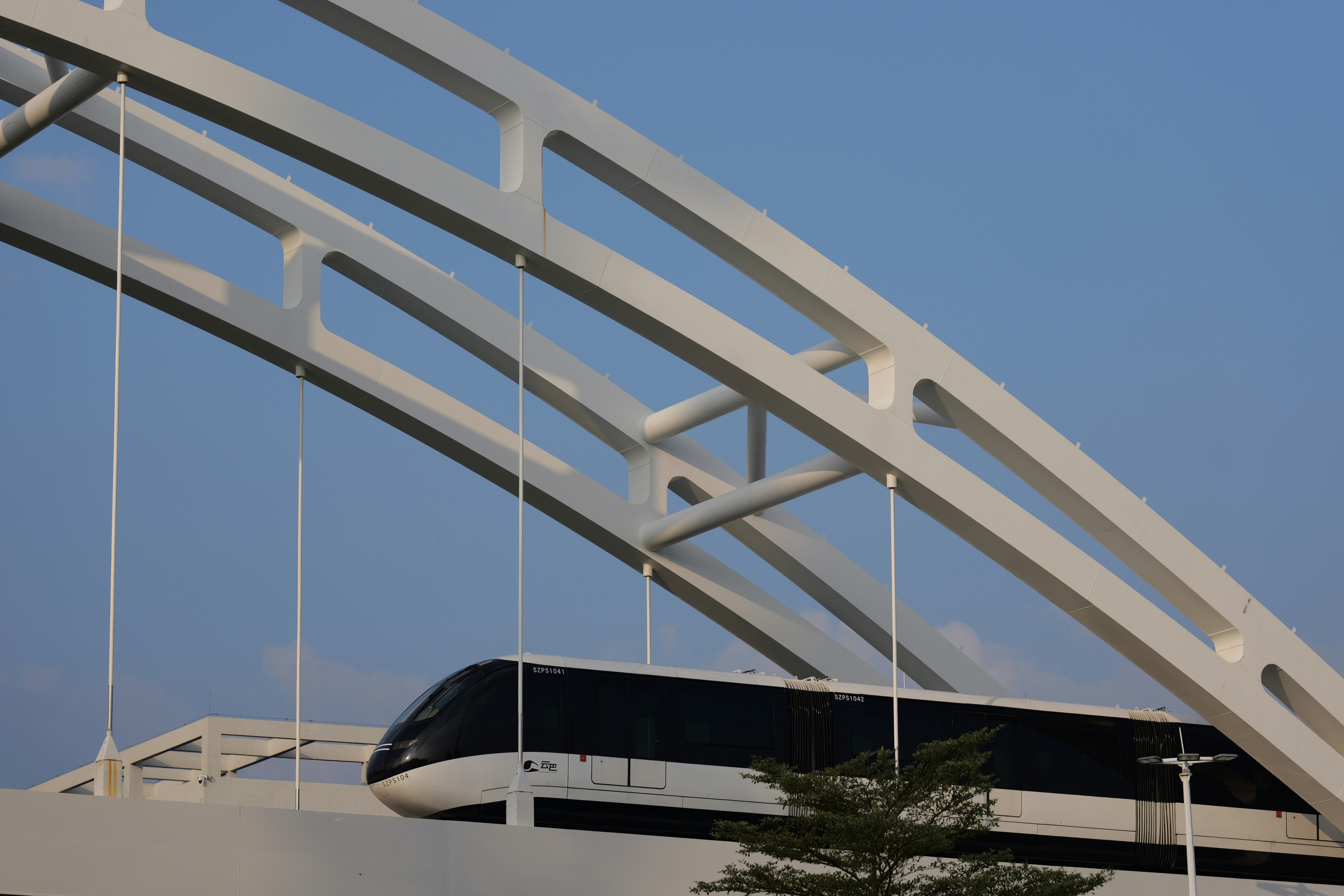 Modern train crossing a white arched bridge.