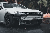 White car with bumper removed outdoors