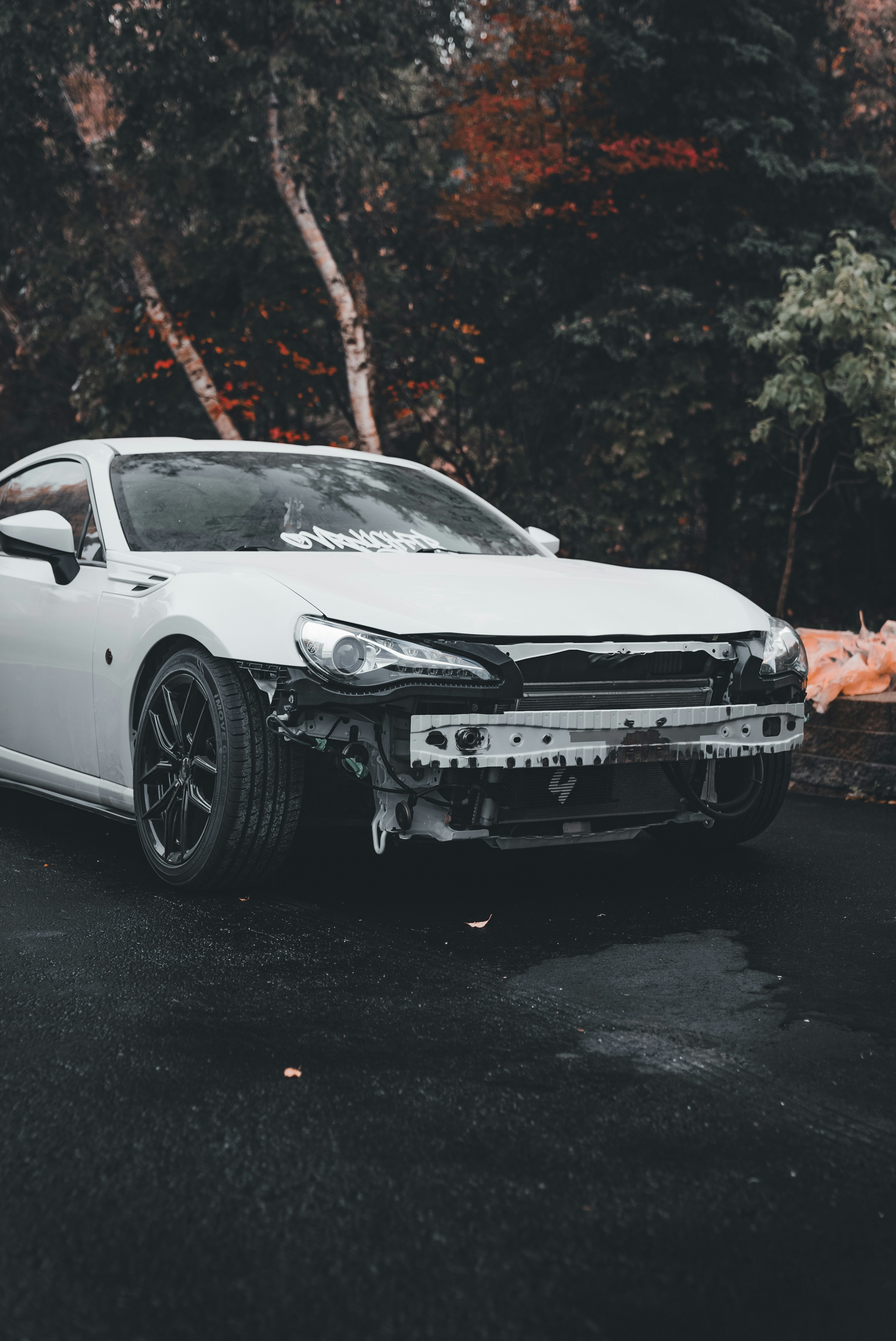 White car with front bumper removed outdoors