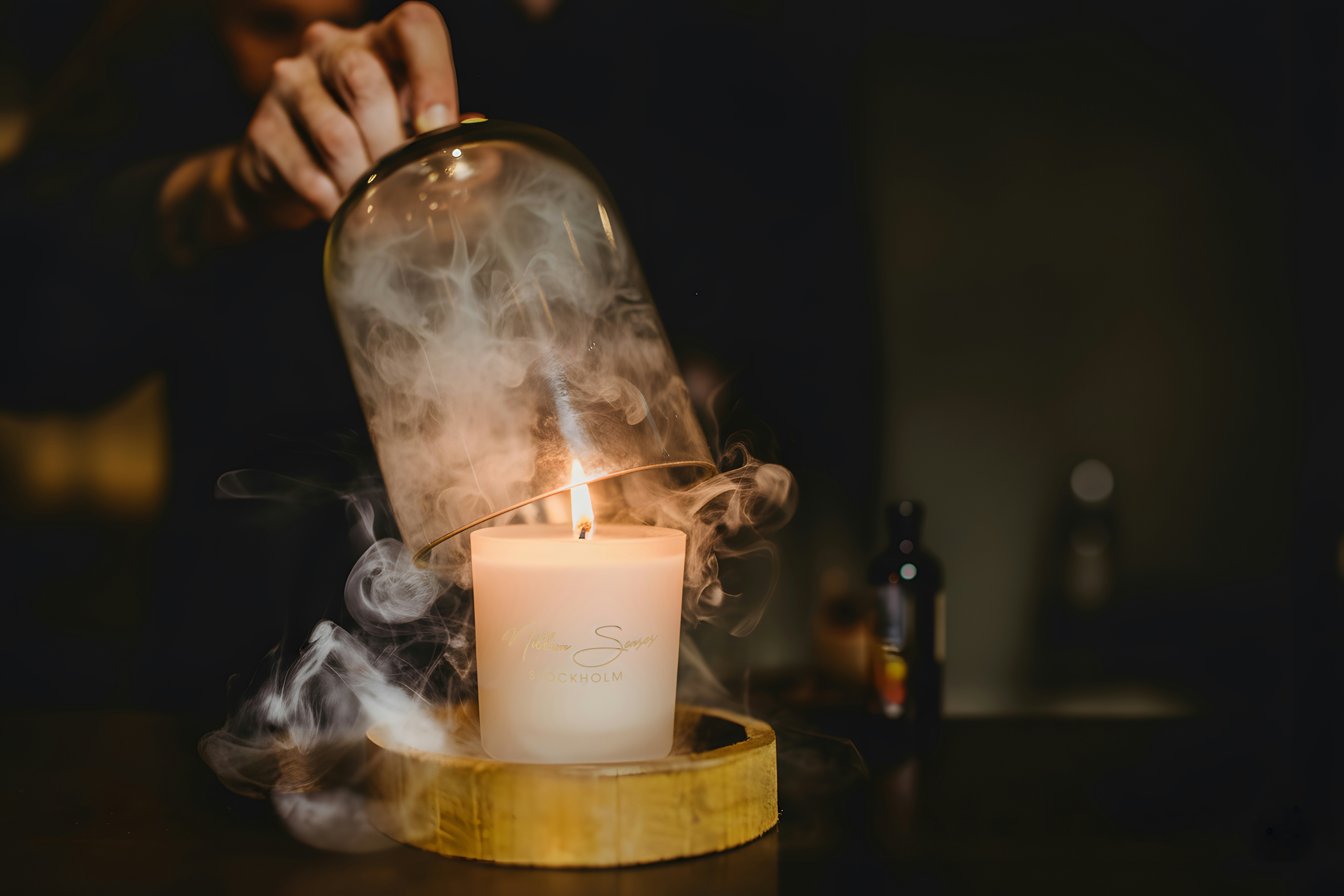 Candle smoke escapes from under a glass dome.