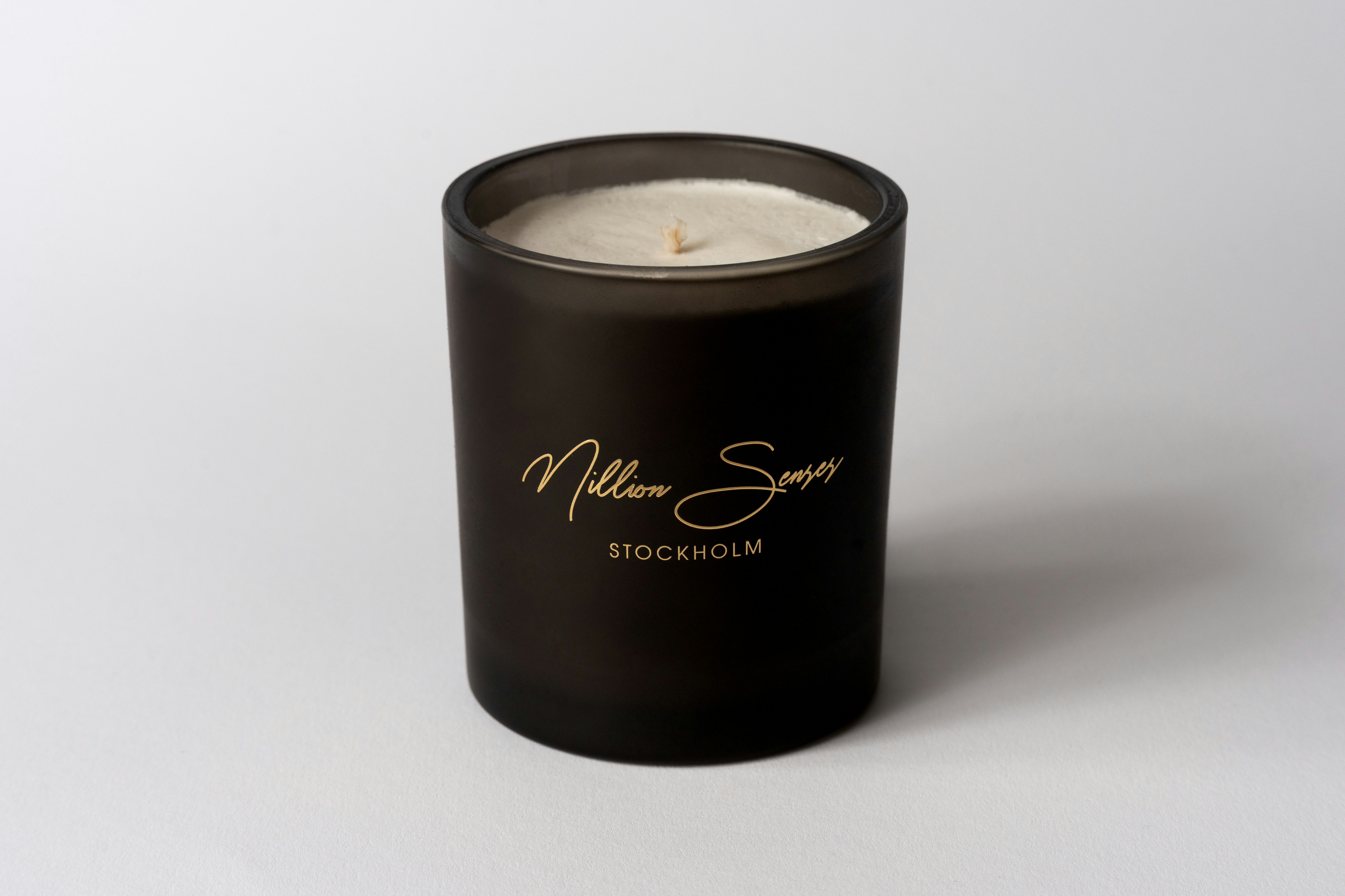 A dark glass candle with gold lettering.
