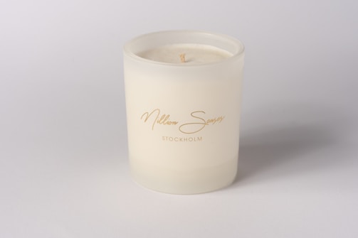 A white candle in a frosted glass container.