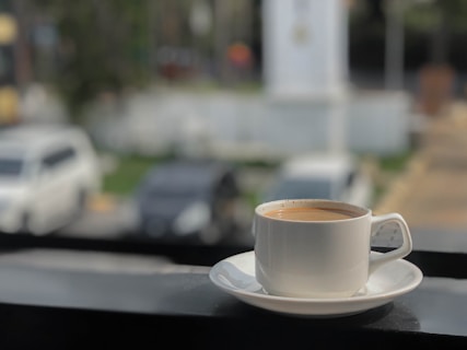 Cup of coffee on a saucer with cars blurred background