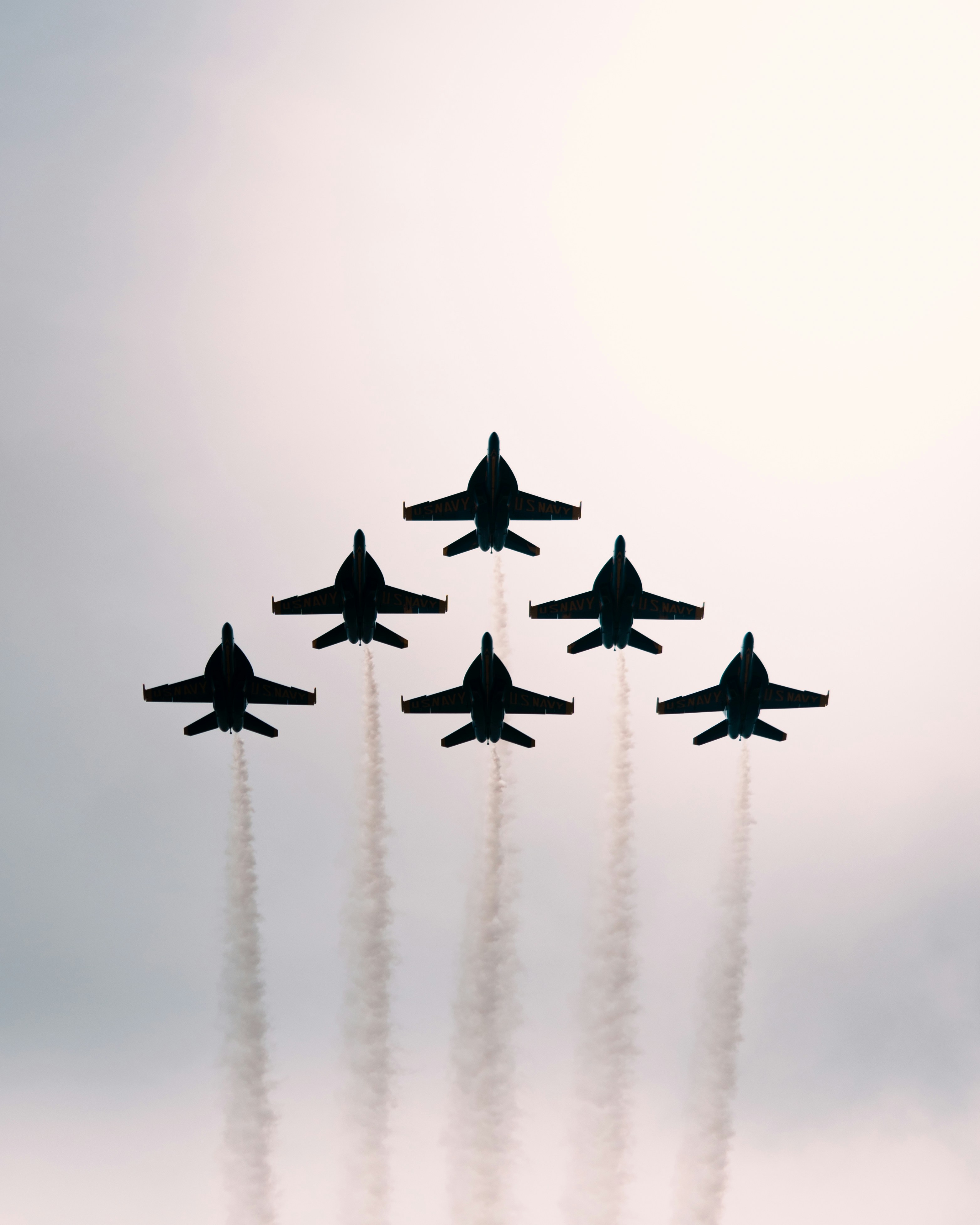 Seven fighter jets fly in formation leaving smoke trails.