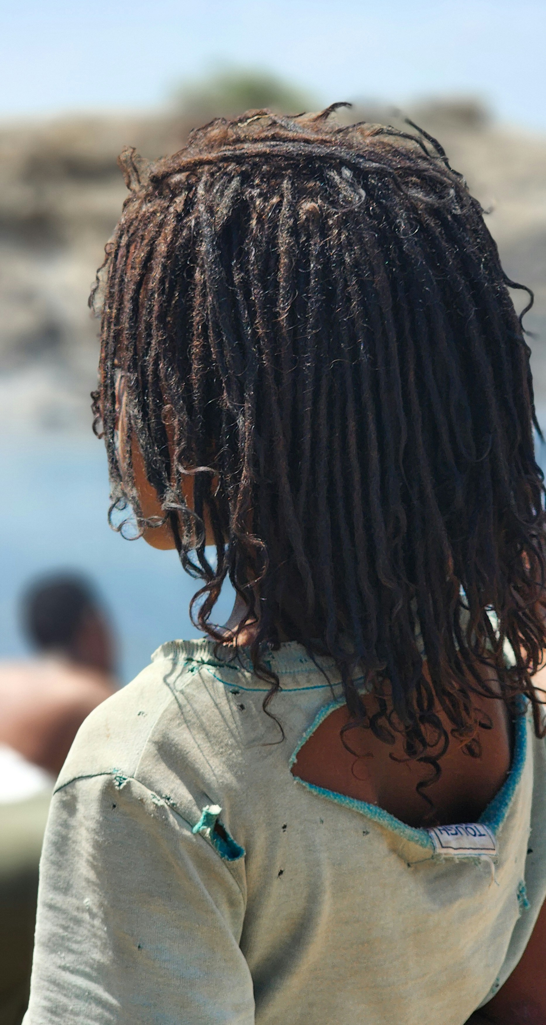 Young person with dreadlocks wearing a torn shirt