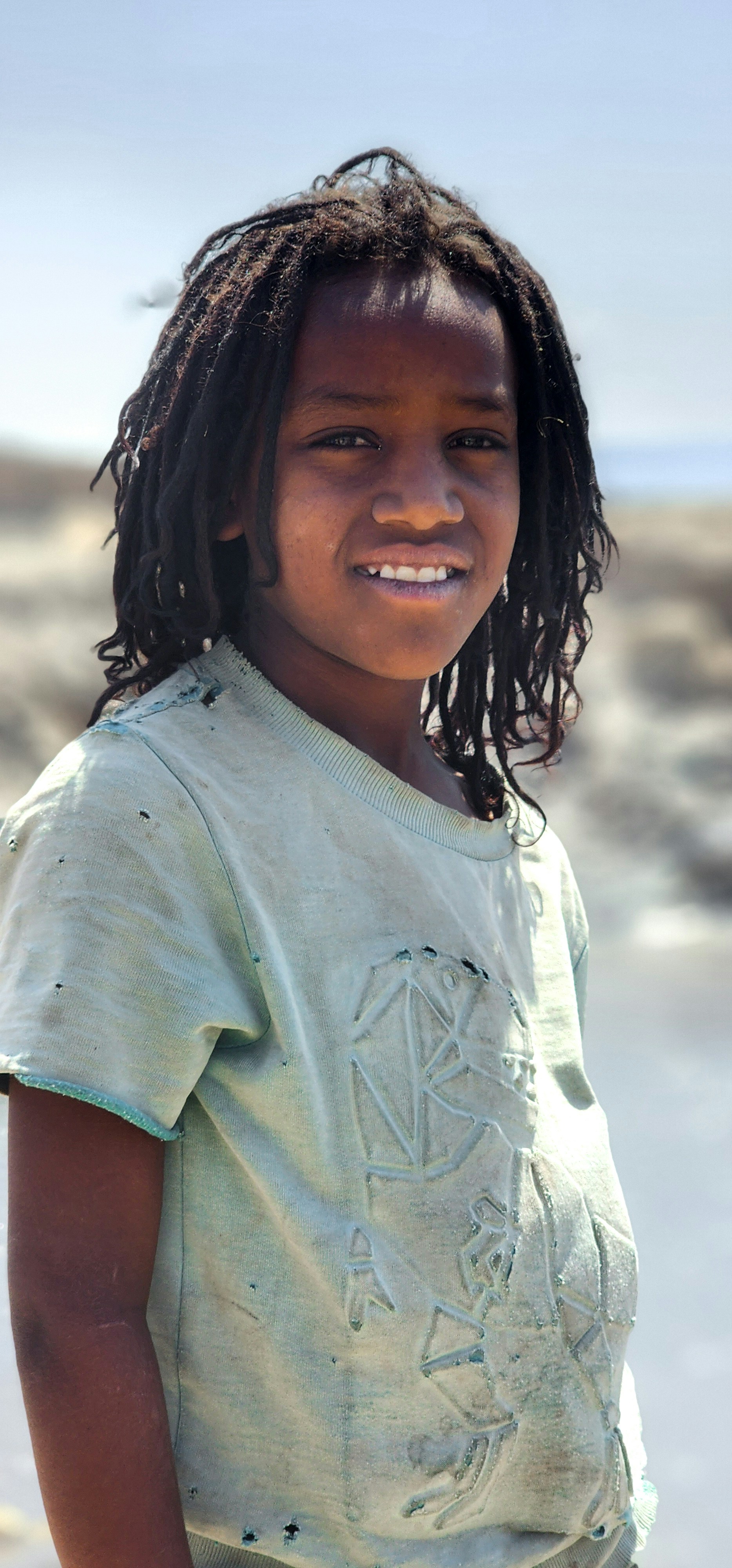 A young child with dreadlocks smiles warmly