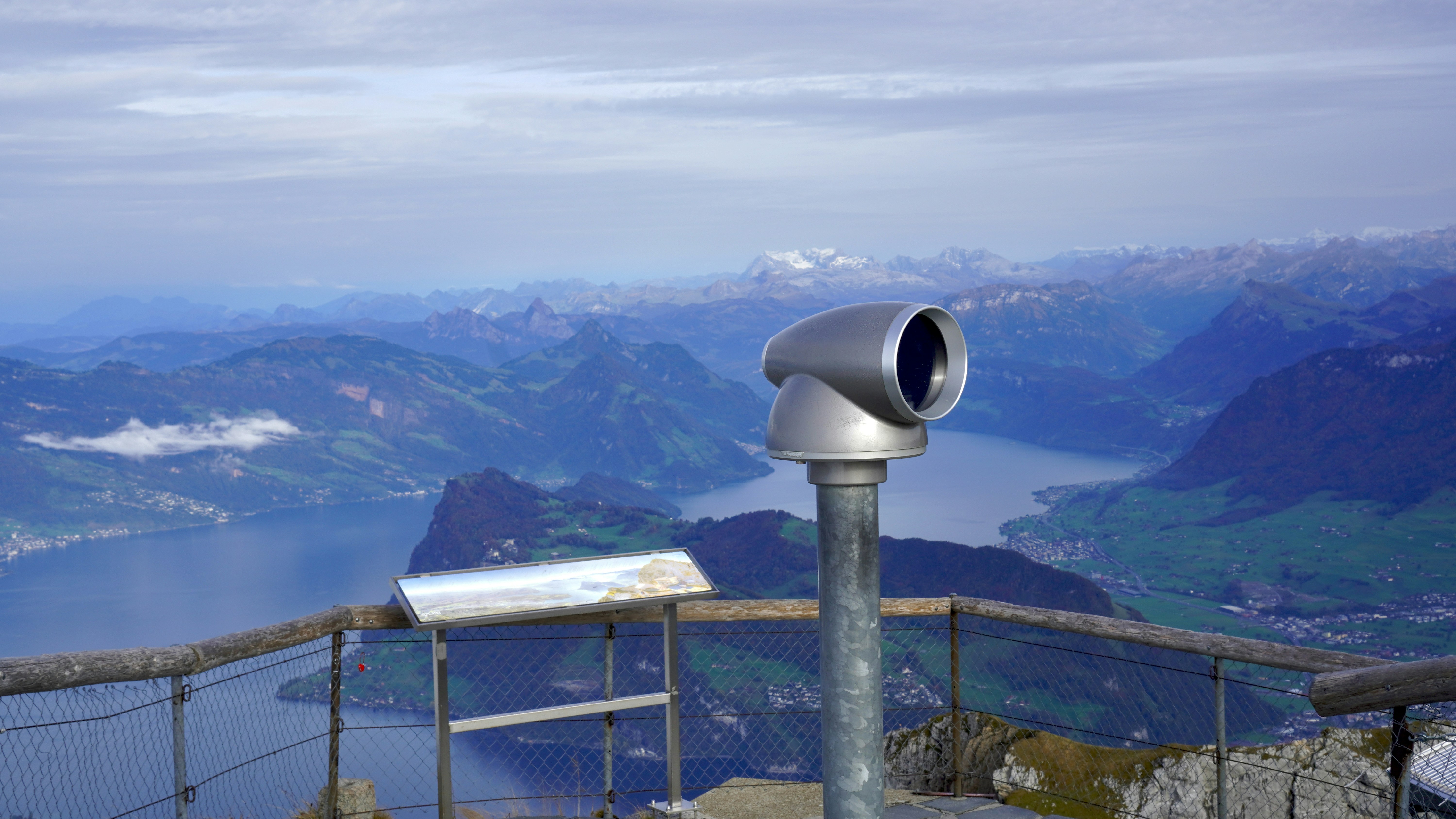 Binoculars on mountain overlook with lake and hills