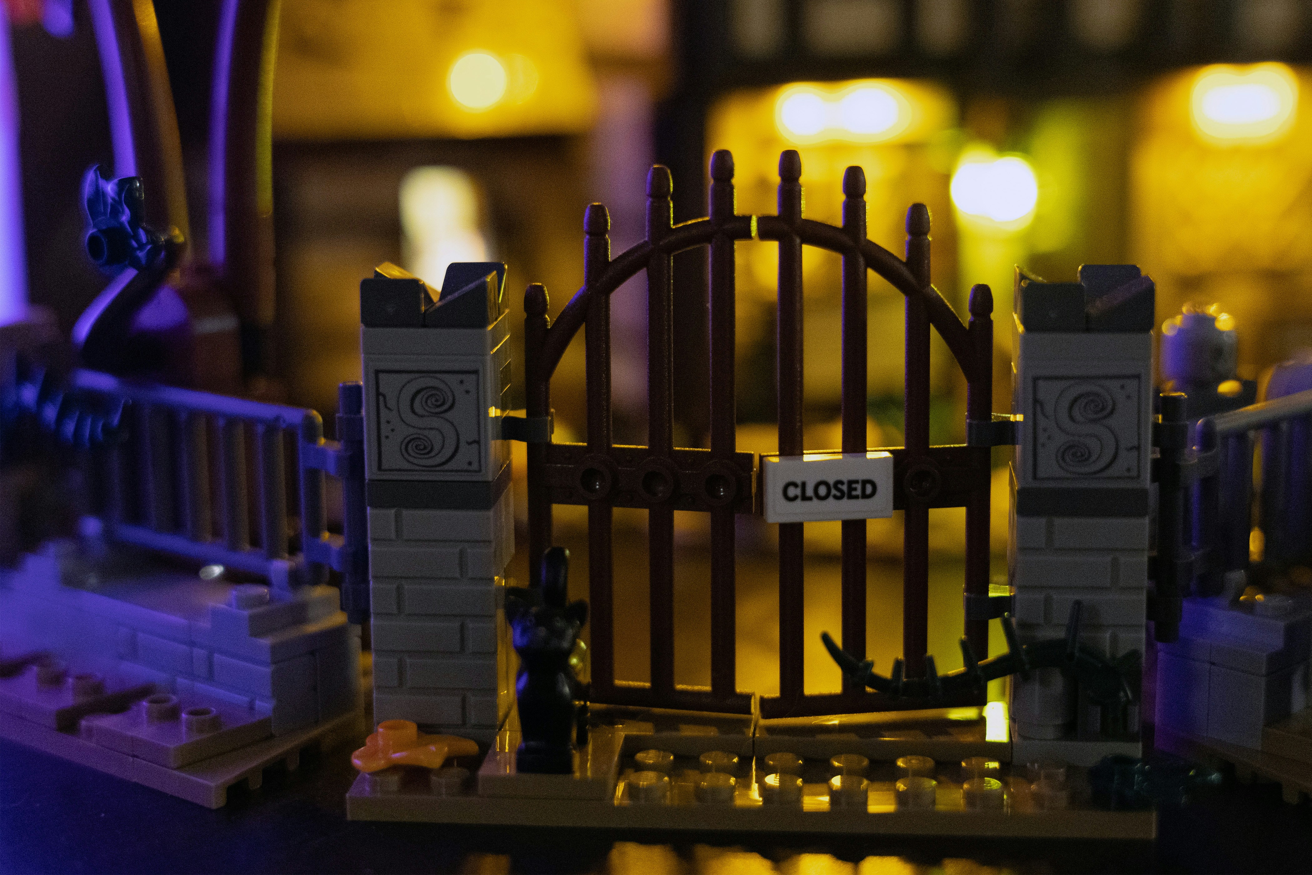 Geschlossenes Holztor mit Steinsäulen und Lichtern.