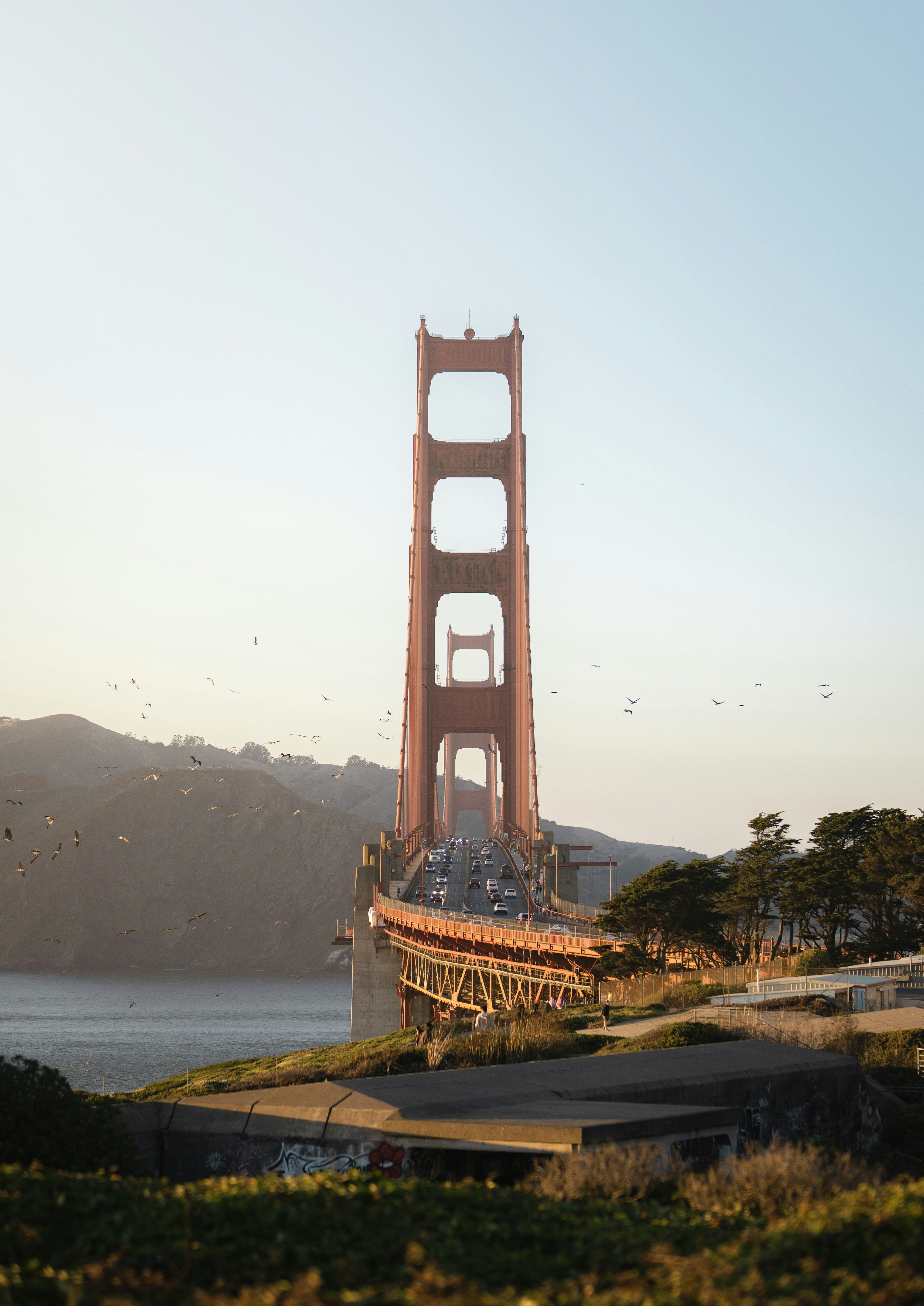 Golden Gate Bridge at sunset with distant hills.