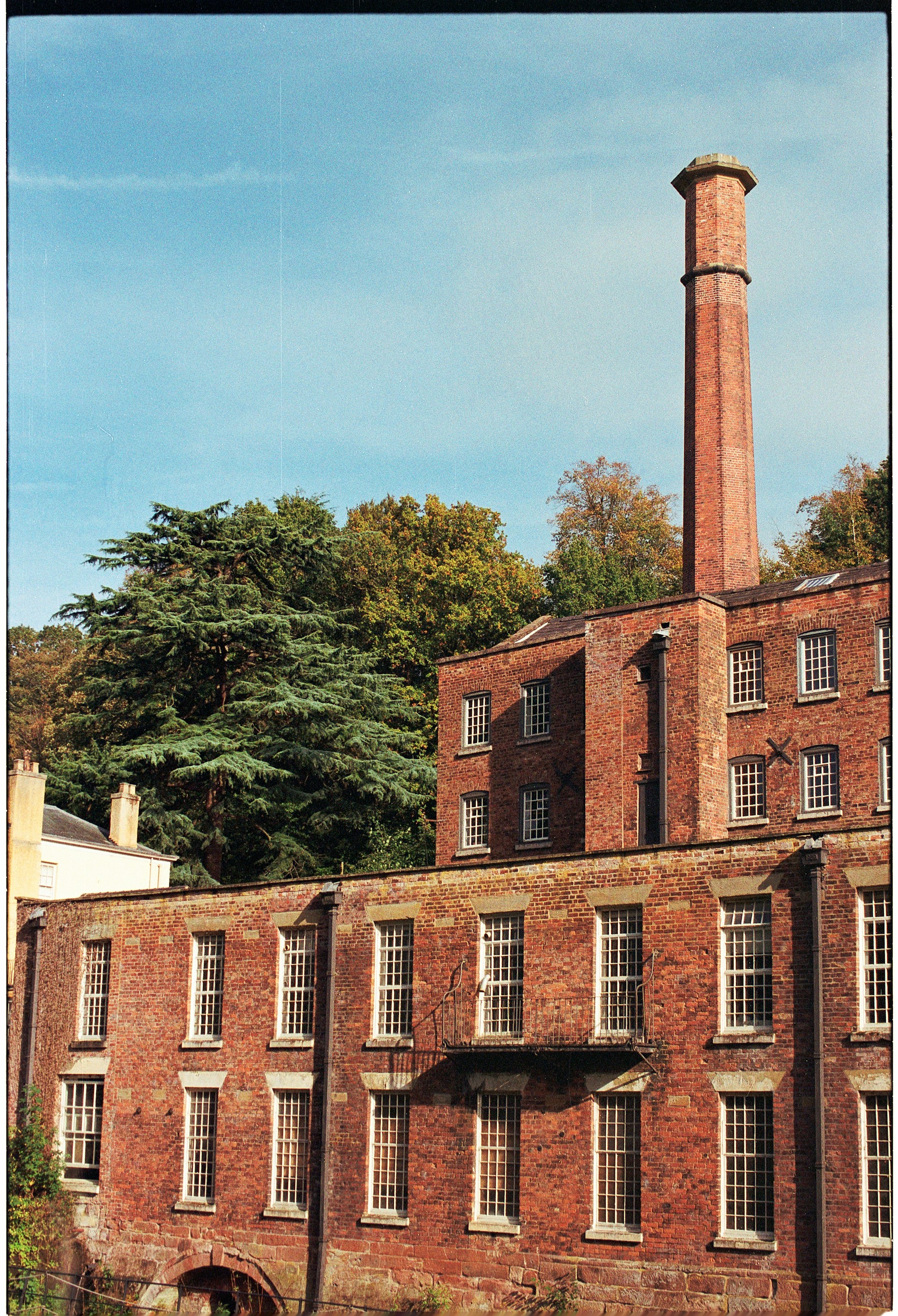 Old brick factory building with tall chimney.