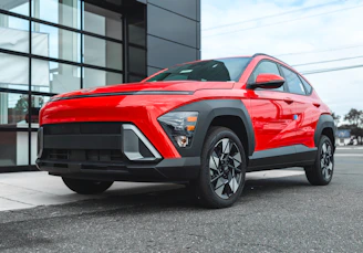A red suv parked outside a modern building.