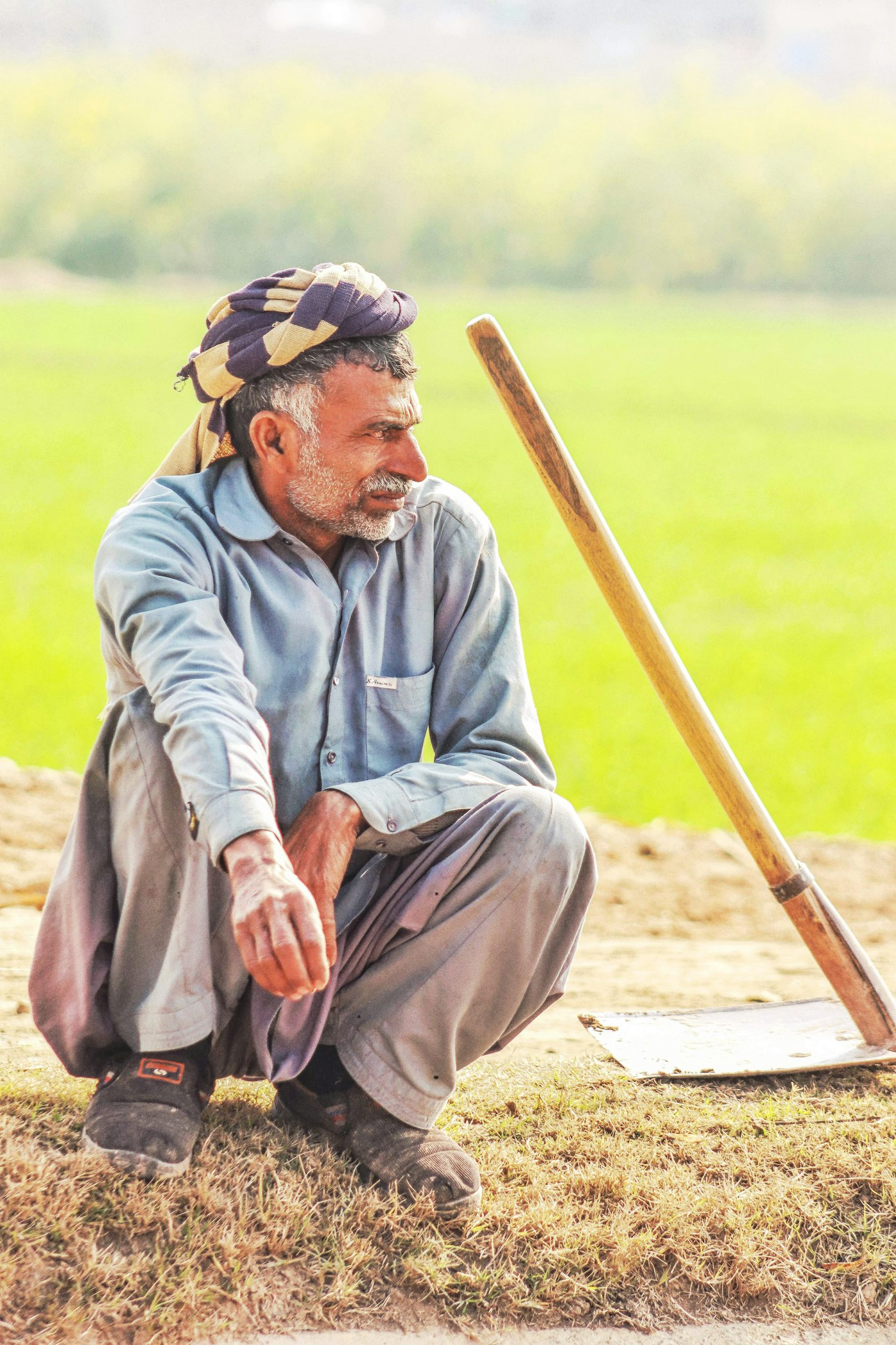 Farmer resting beside his tools in a green field