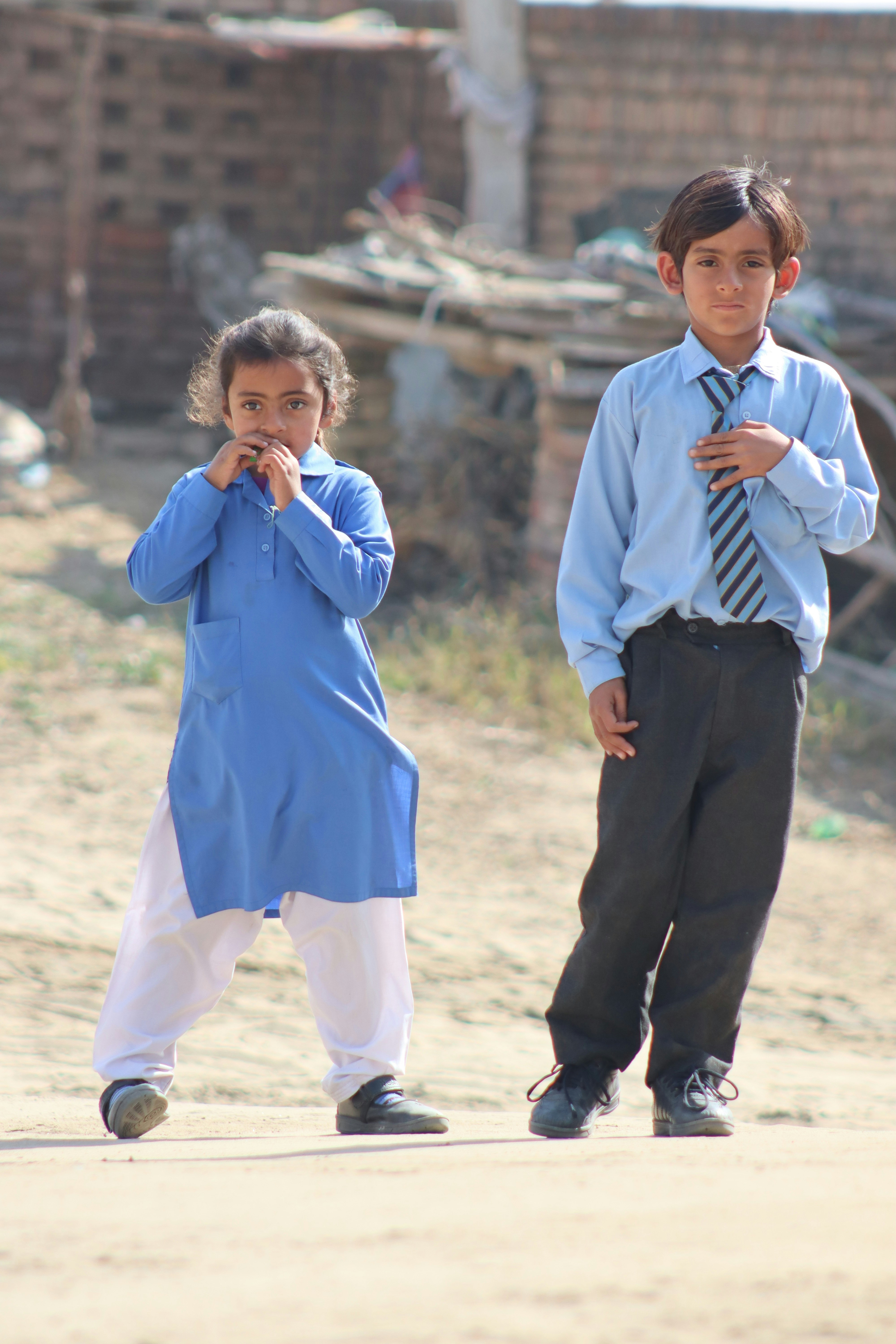 Two young children in school uniforms outdoors