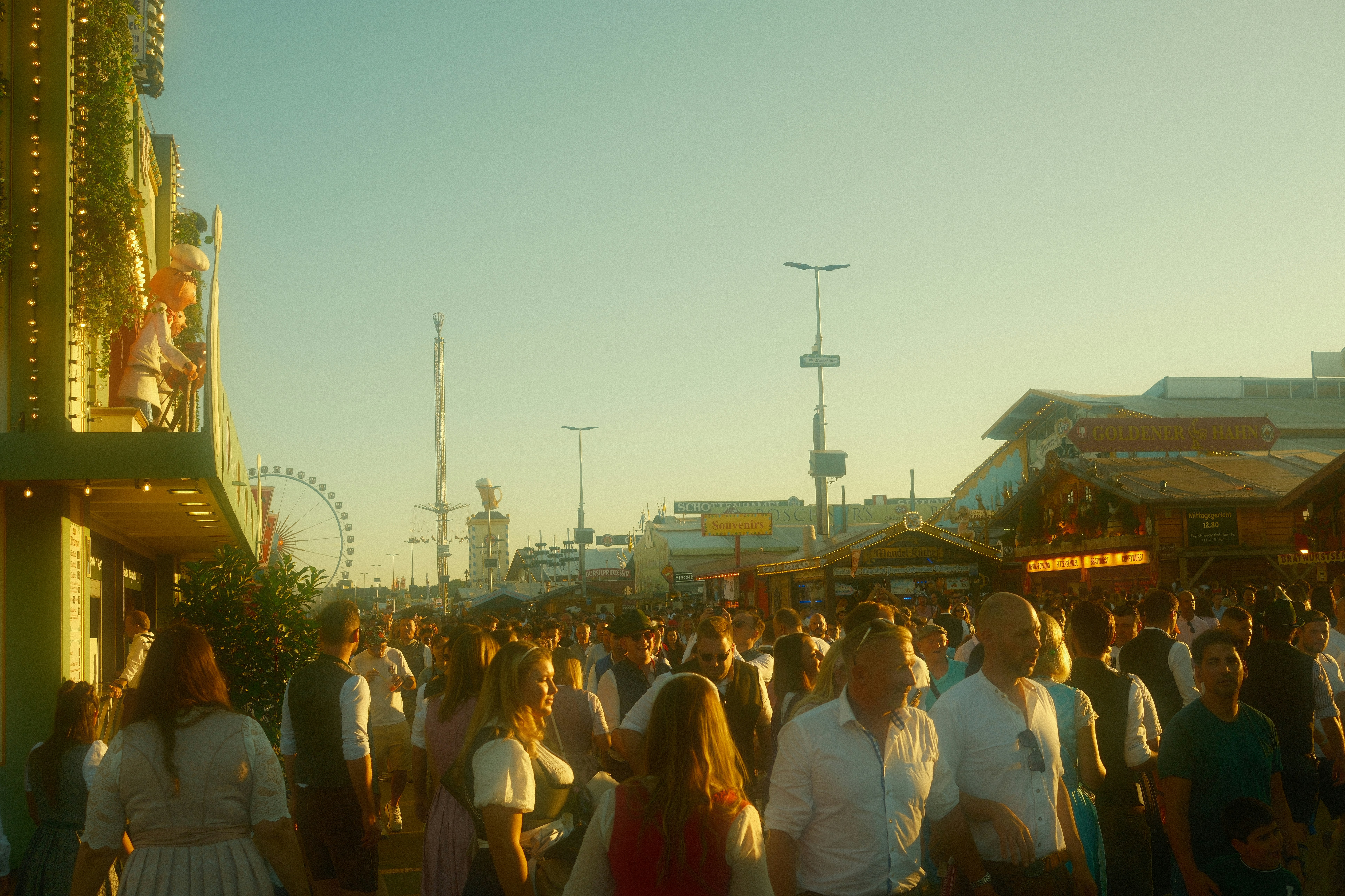 Crowd of people walking through a sunny outdoor festival.