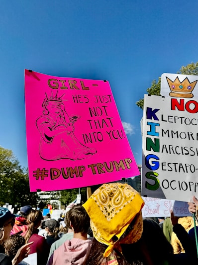 Protestors hold signs at a rally under a blue sky.