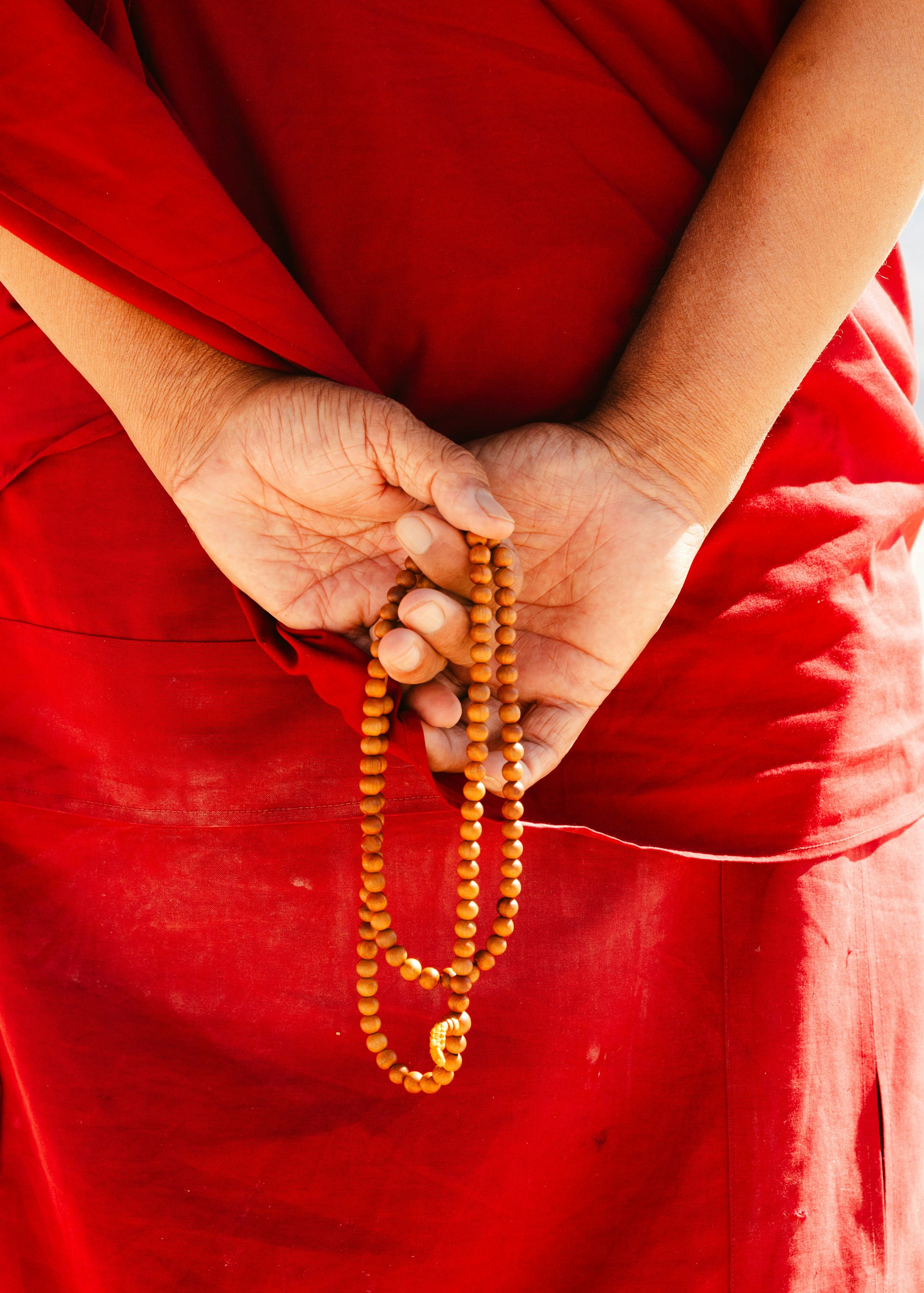 Monk holding prayer beads behind back