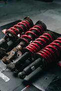 Four red coilover suspension assemblies on a black surface