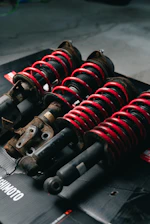 Four red coilover suspension assemblies on a black surface