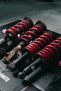 Four red coilover suspension assemblies on a black surface