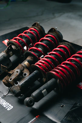 Four red coilover suspension assemblies on a black surface