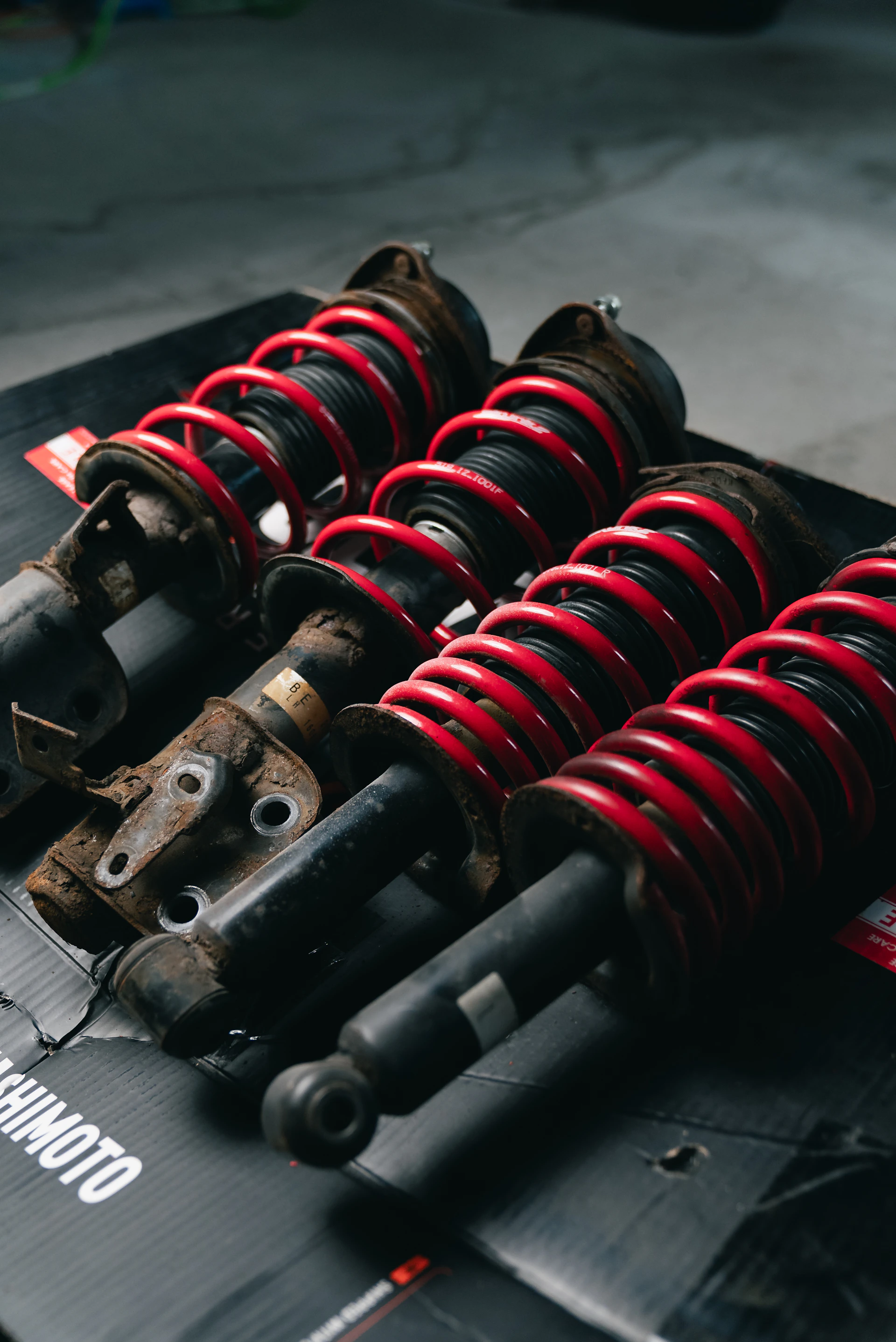 Four red coilover suspension assemblies on a black surface