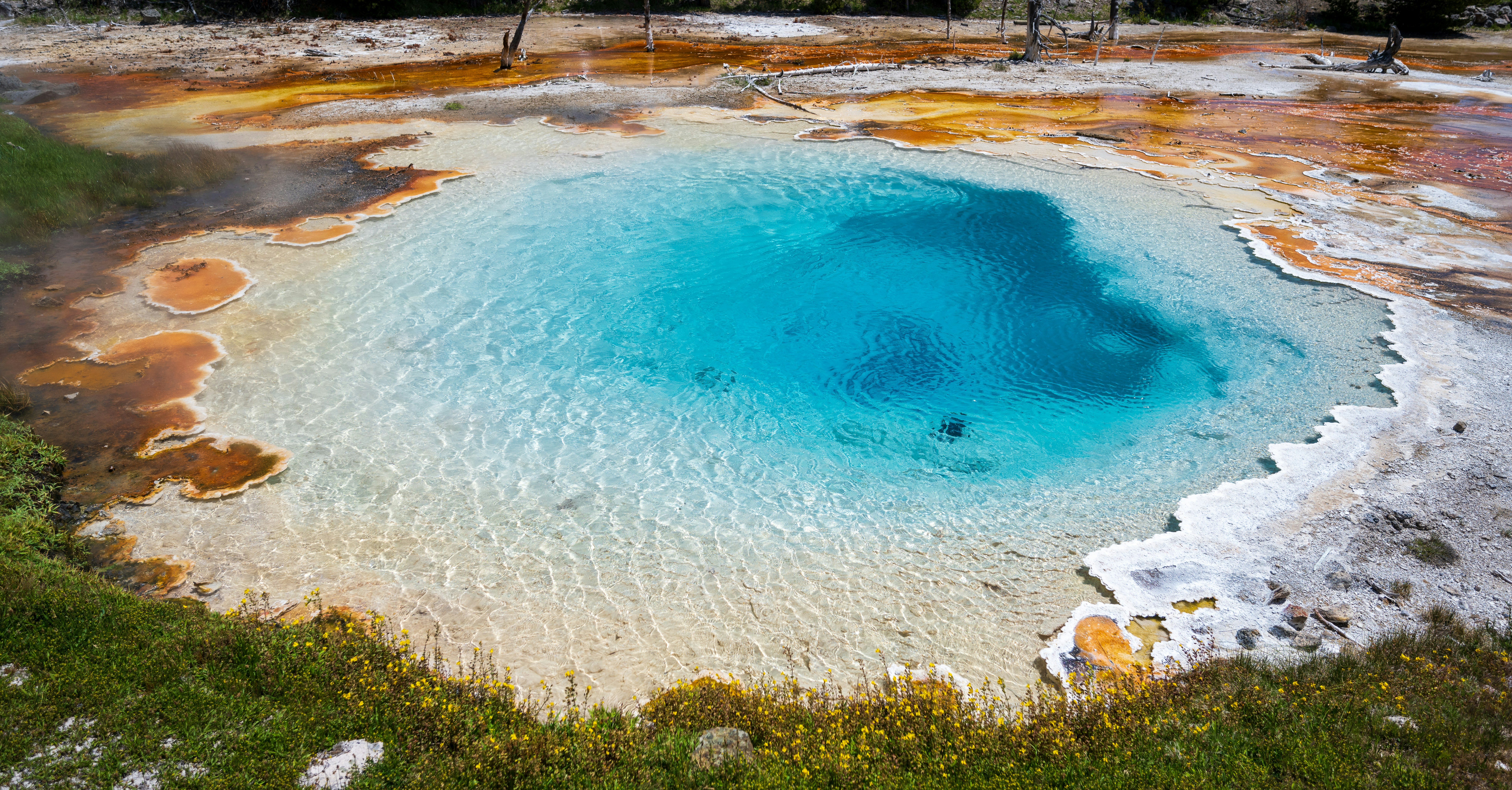 Vibrant blue hot spring with colorful mineral deposits