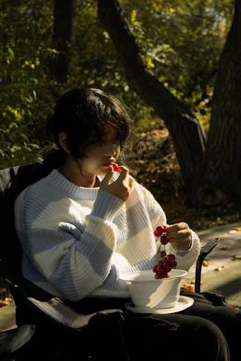 Young woman eating grapes in a park