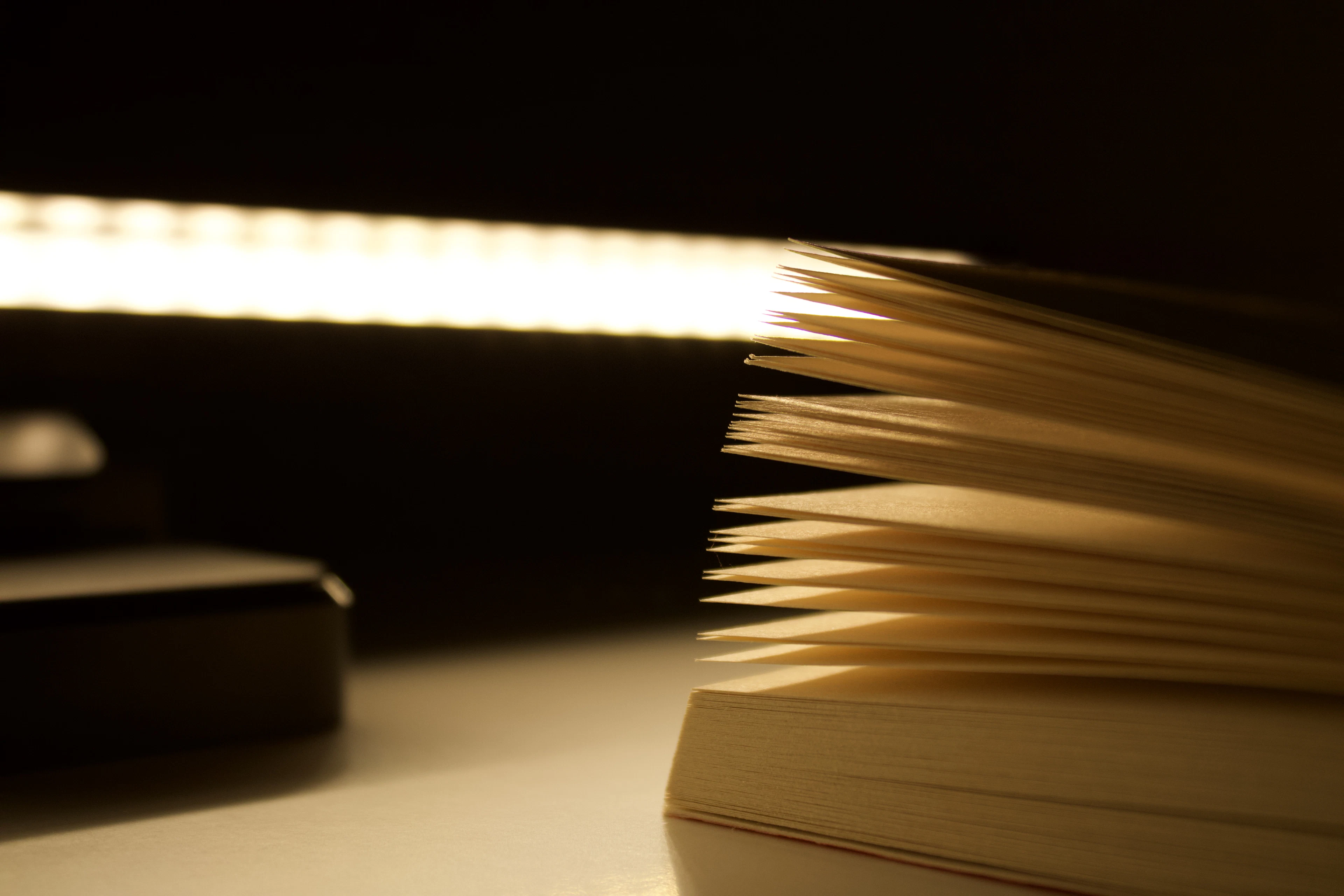 Livro aberto com as páginas iluminadas na penumbra