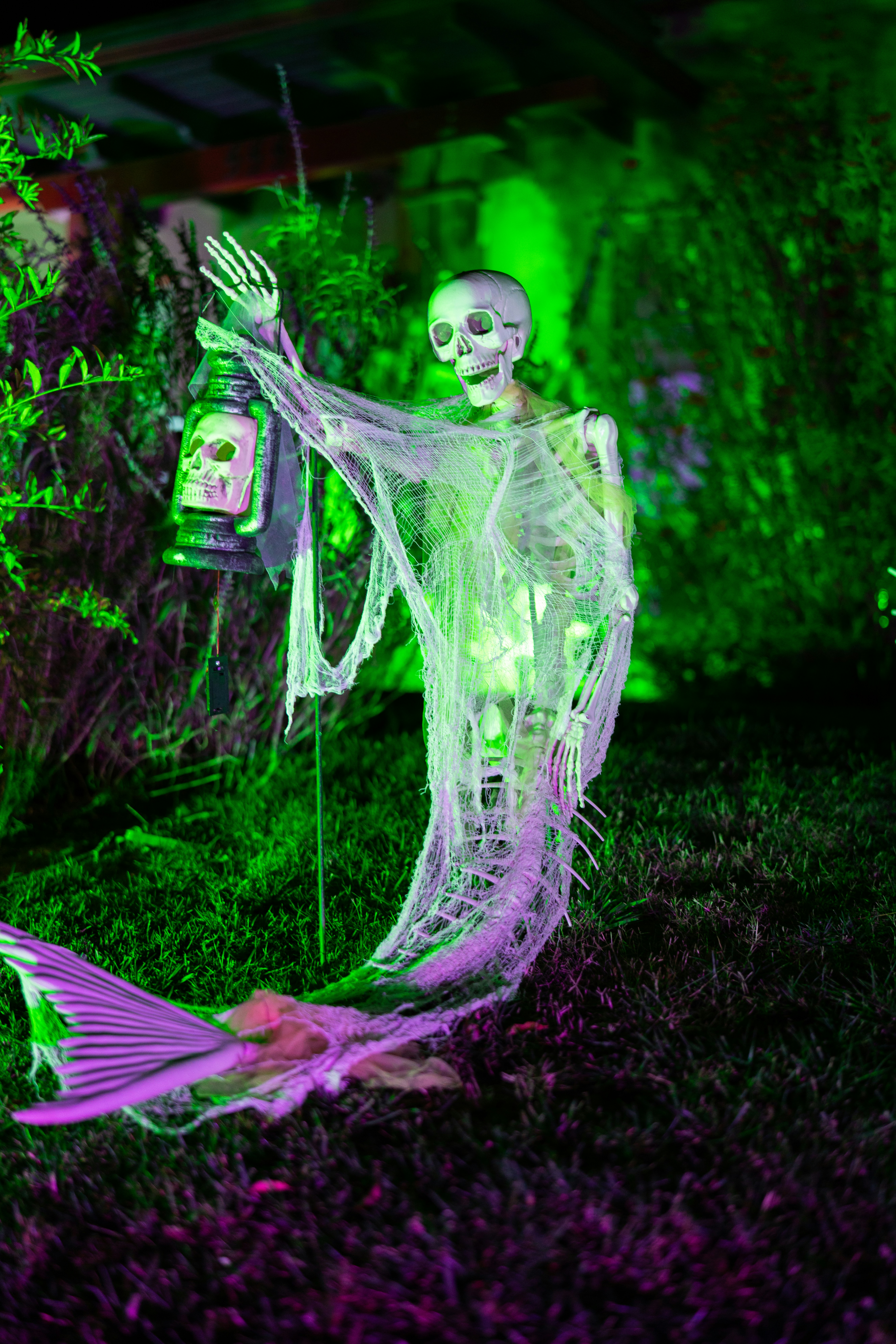 Sereia esqueleto com lanterna em luz verde e roxa