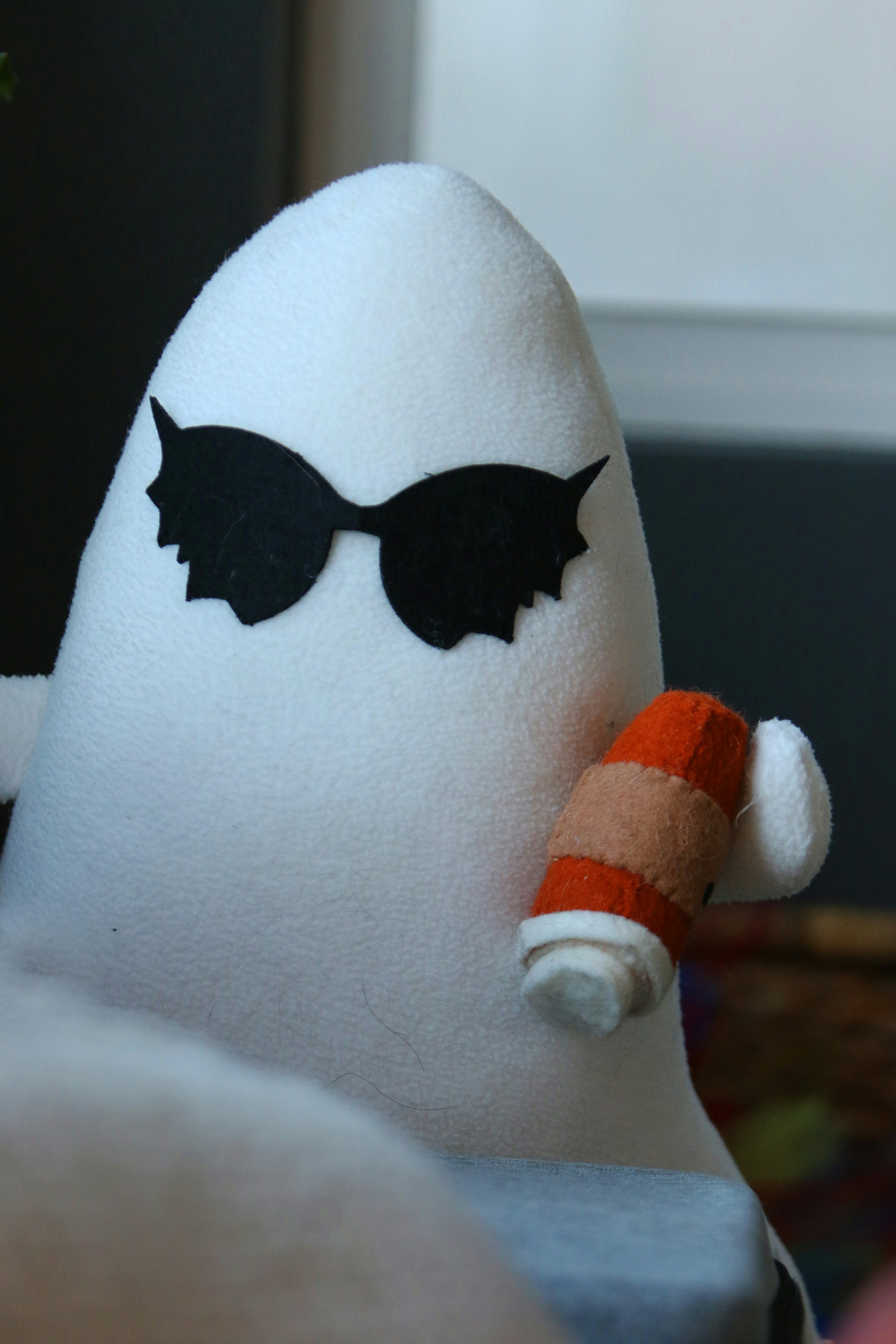 A white ghost wearing sunglasses holds a drink.