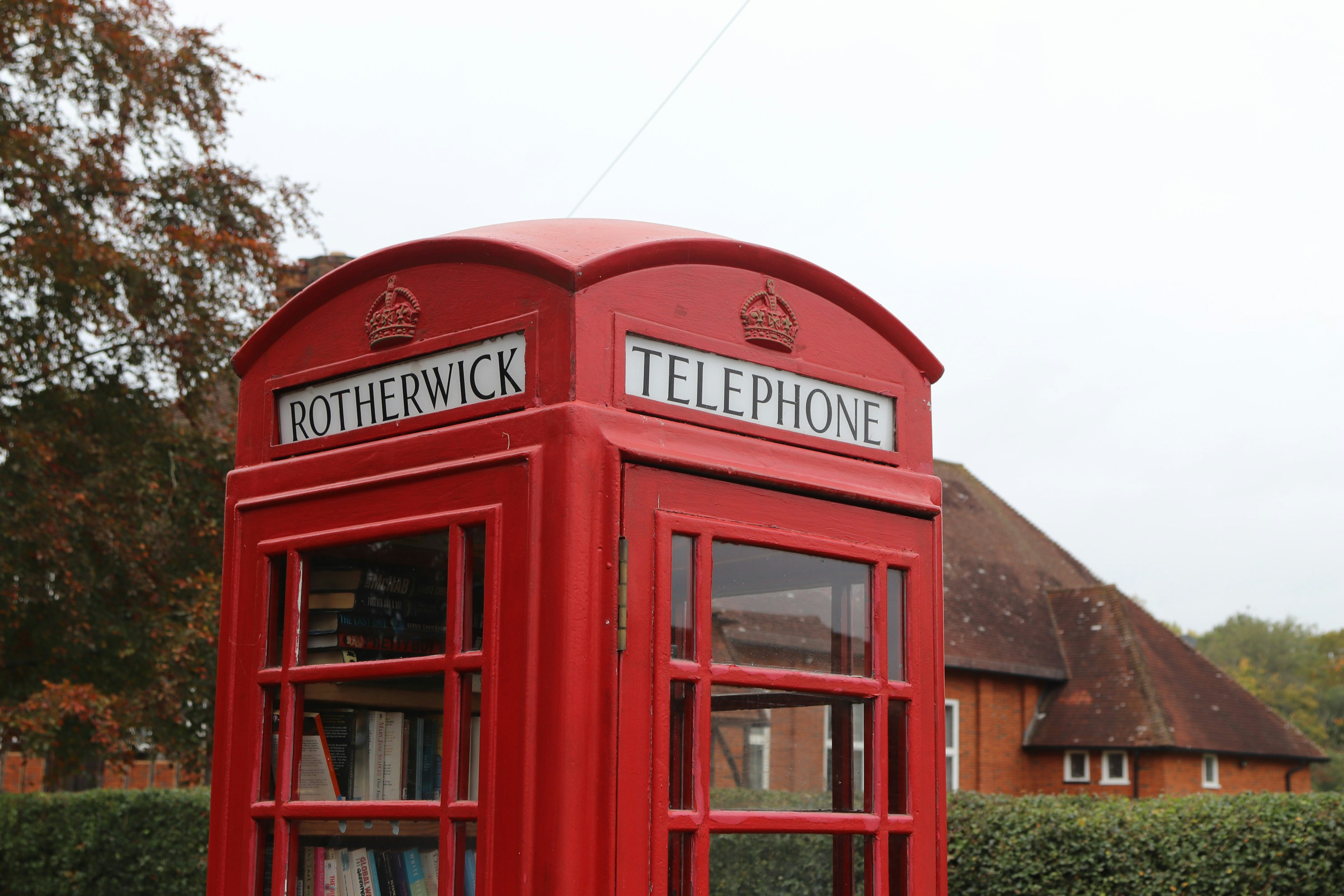 Red british telephone booth with trees and building