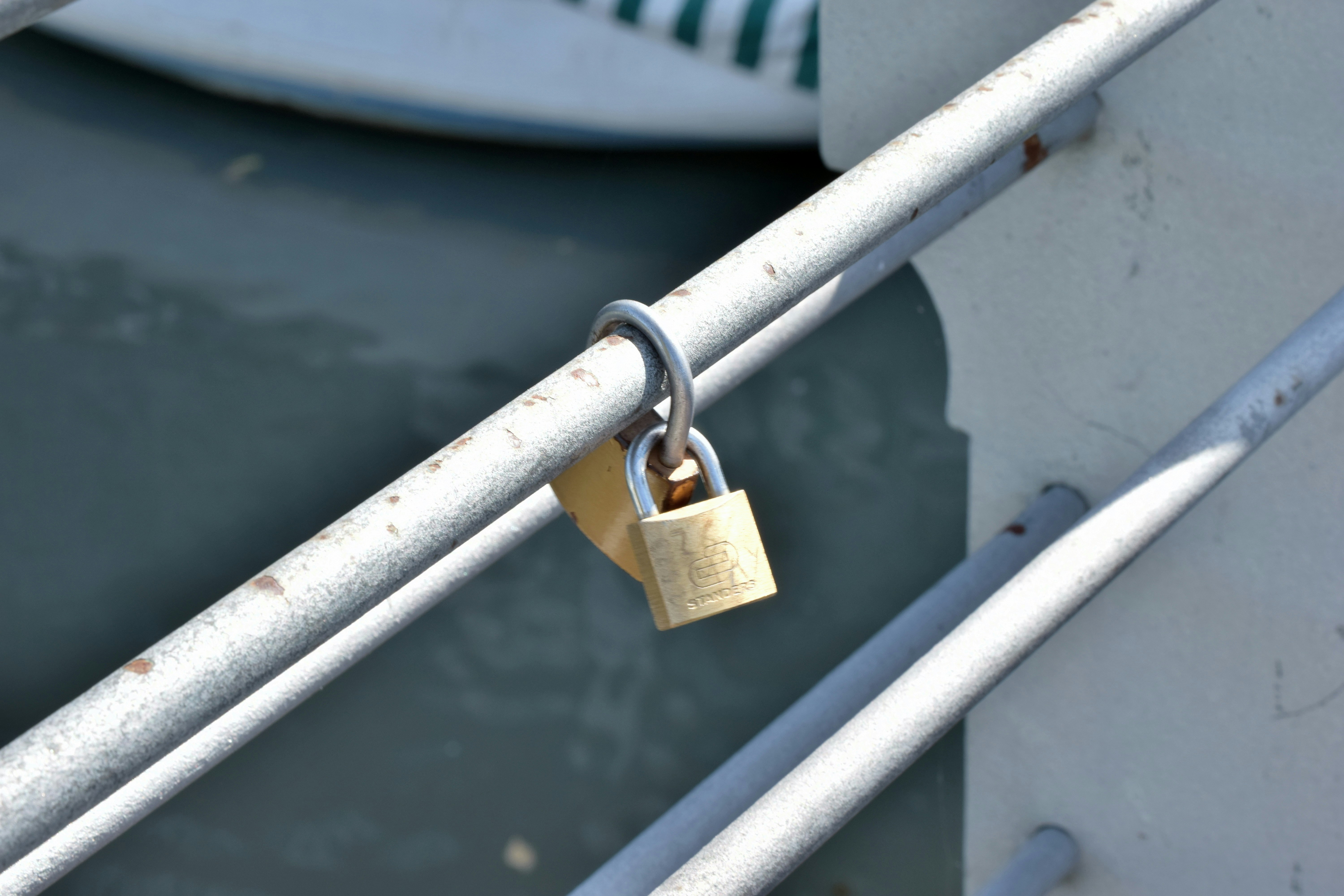 Two padlocks hang from a metal railing.