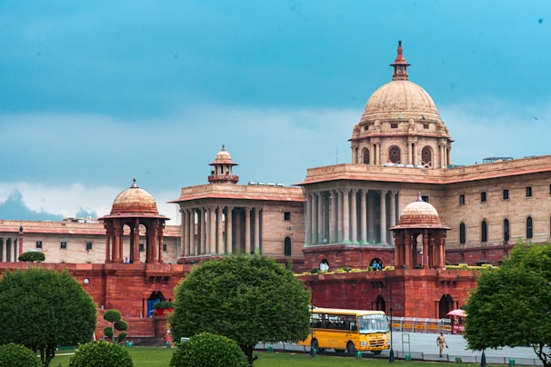 Grand sandstone building with domes under a cloudy sky.