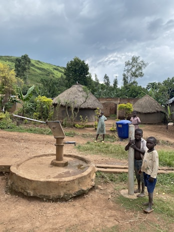 Children stand by a water pump in a village.