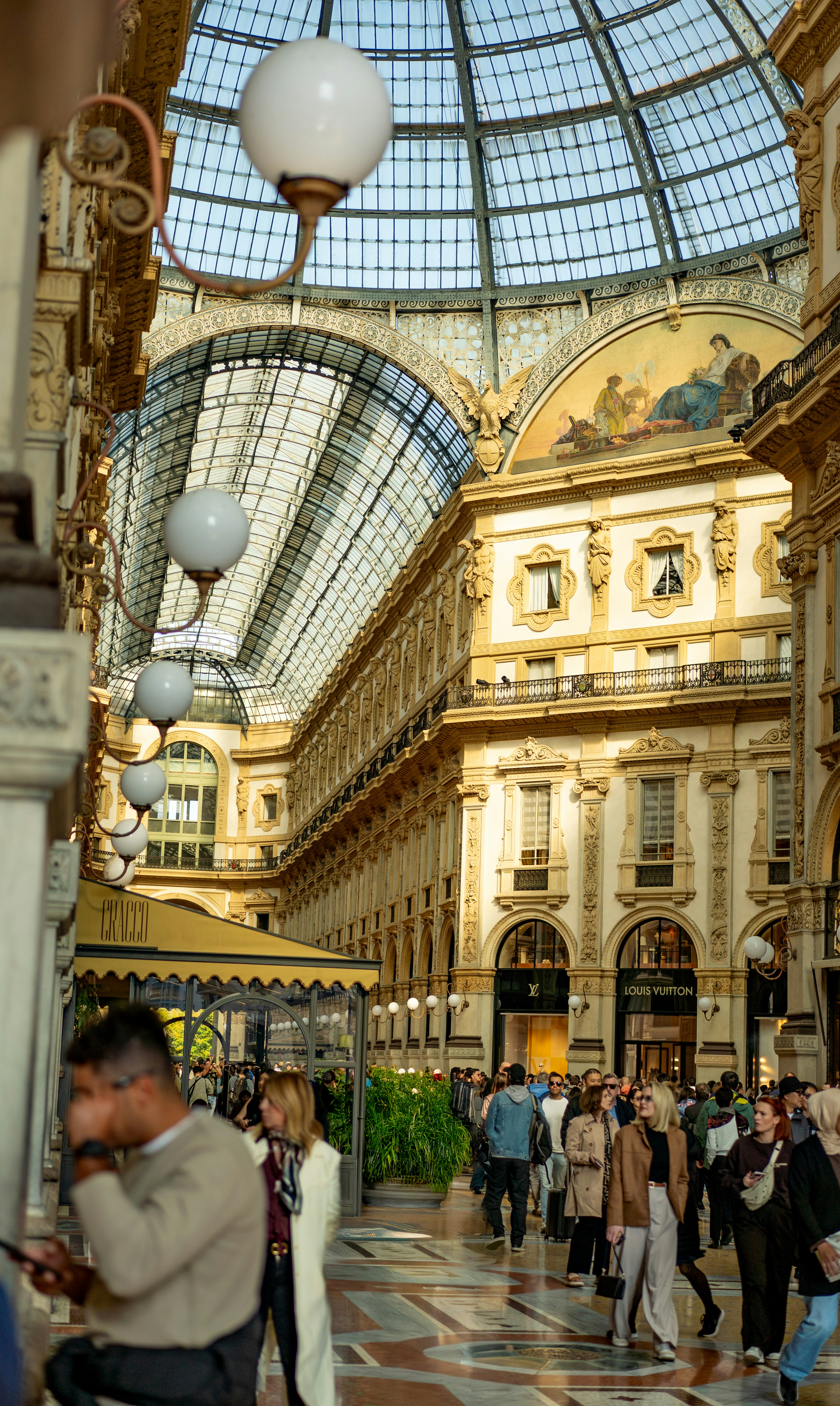 웅장한 유리 돔 아케이드 안을 걷는 사람들