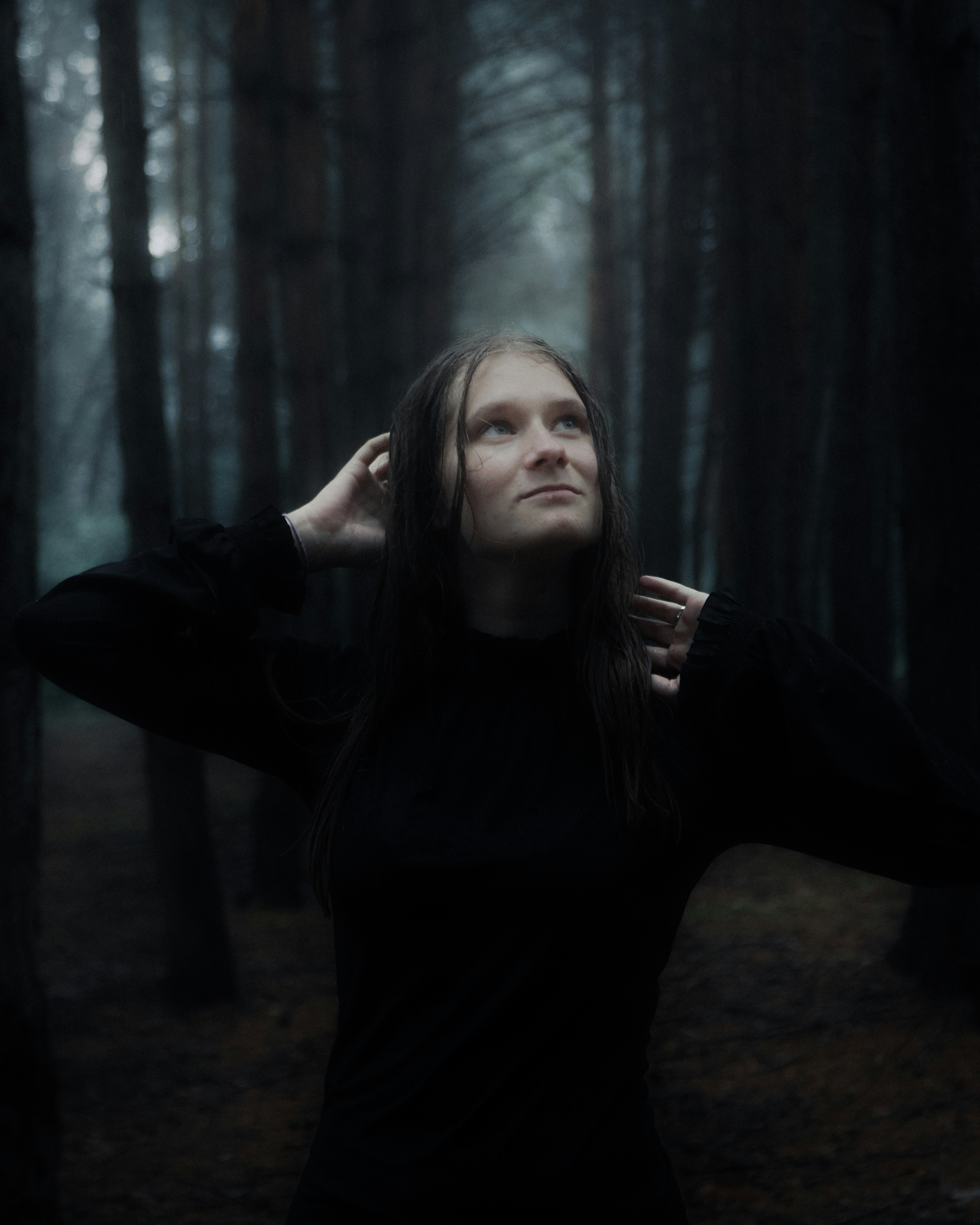 A person looking up in a dark forest.