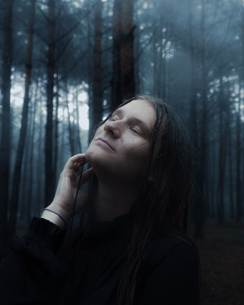 Woman with eyes closed in a misty forest