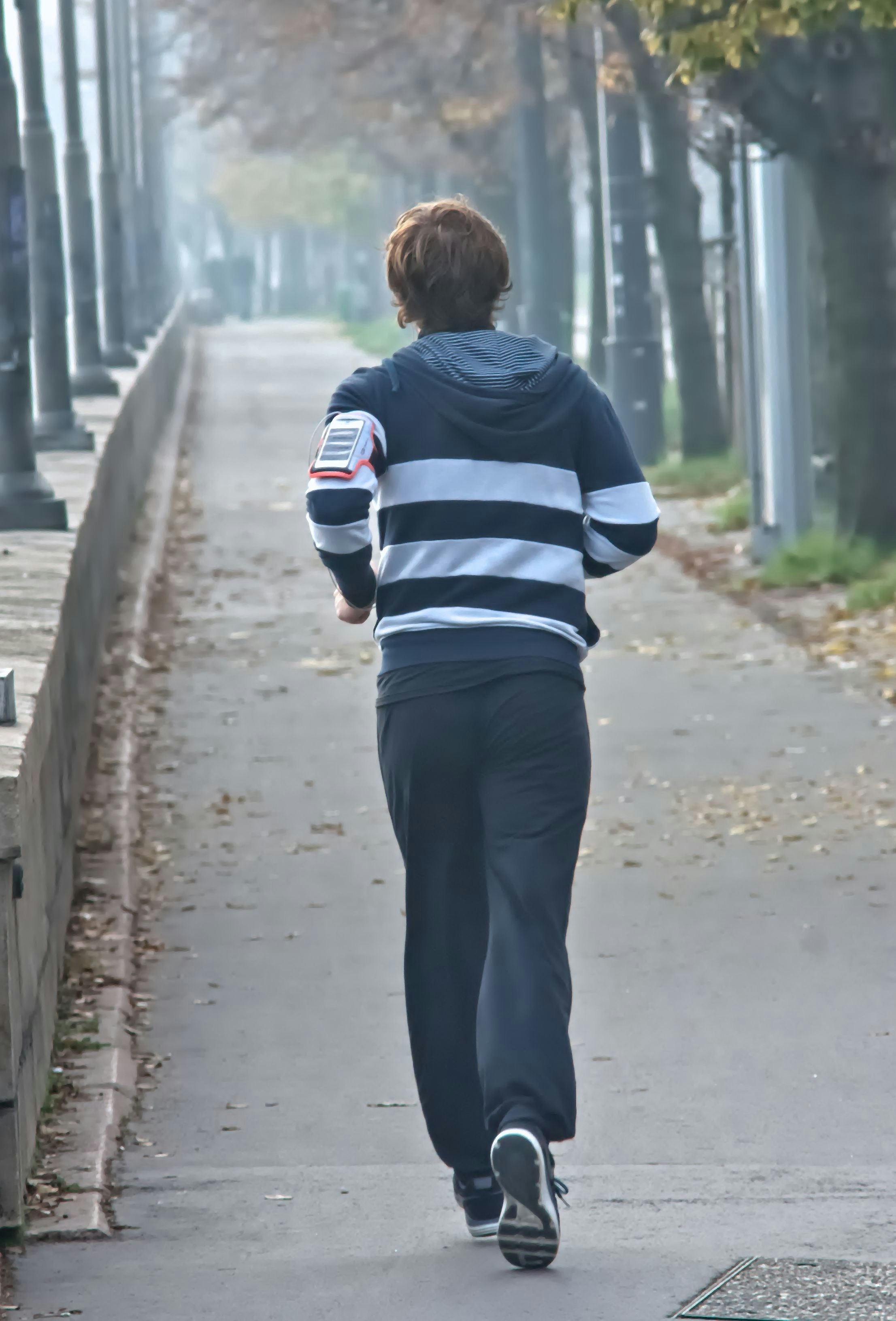Person running on a foggy path beside trees.