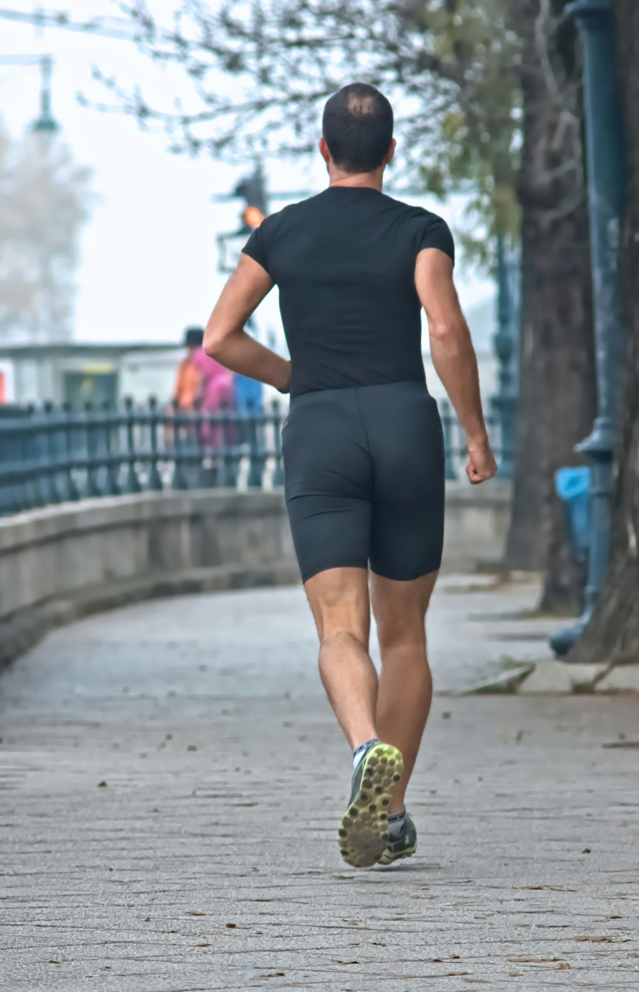 Man running on a paved path next to trees.