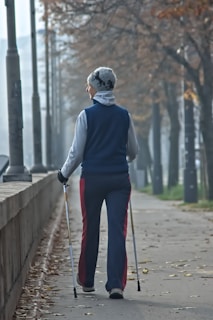 Woman with walking poles on a tree-lined path