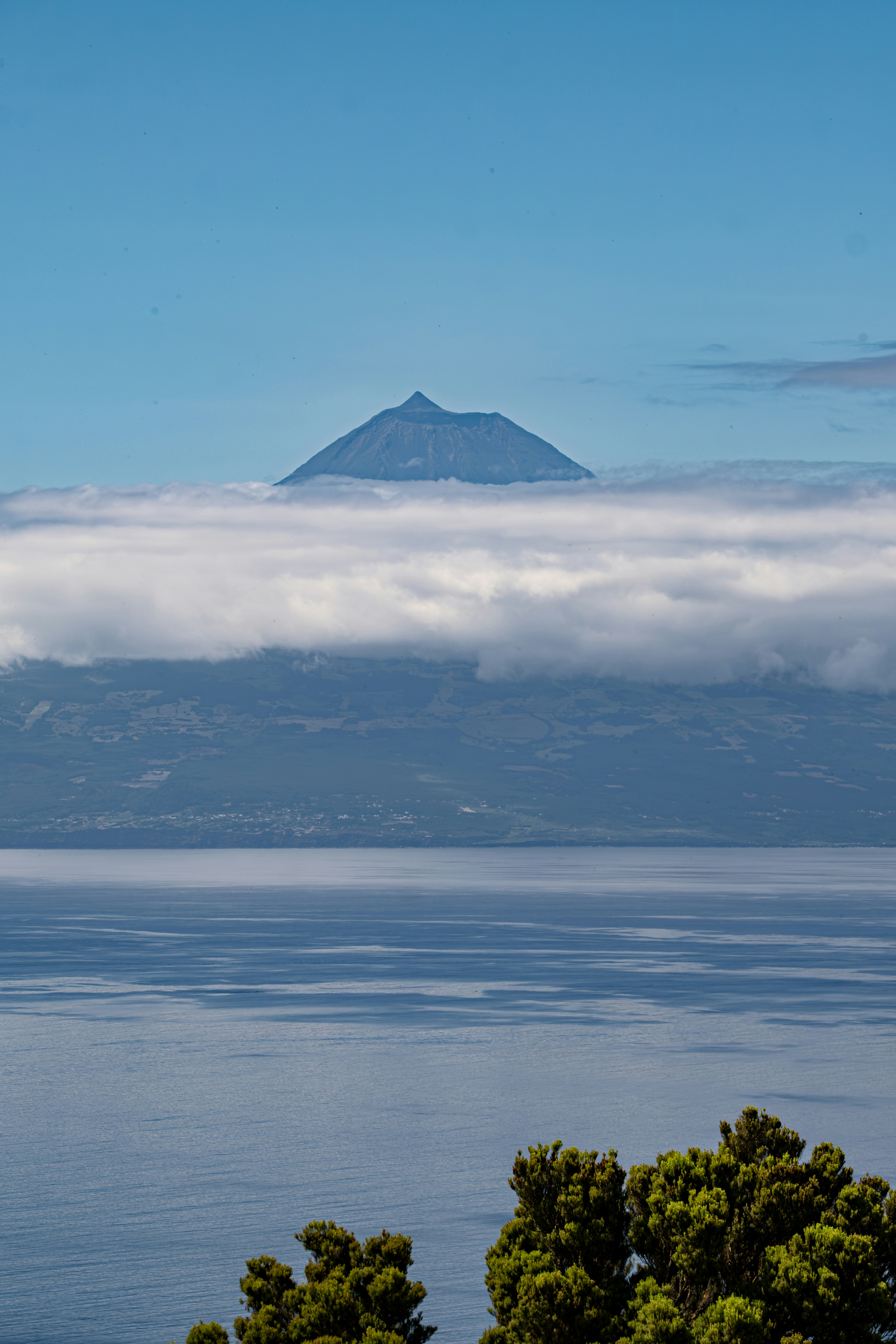 Volcano peak emerges from clouds above ocean