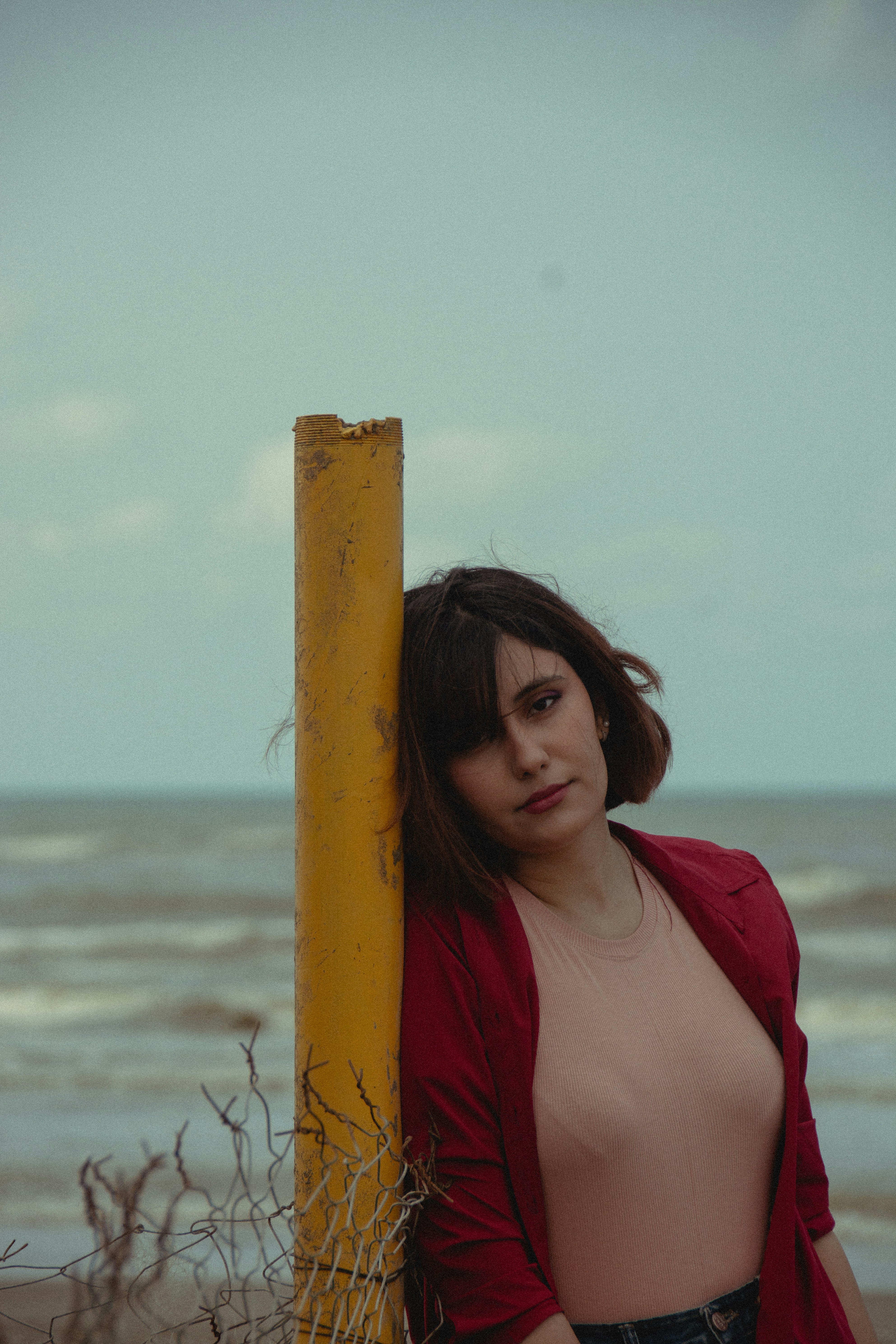 Mulher se inclina no poste amarelo na praia