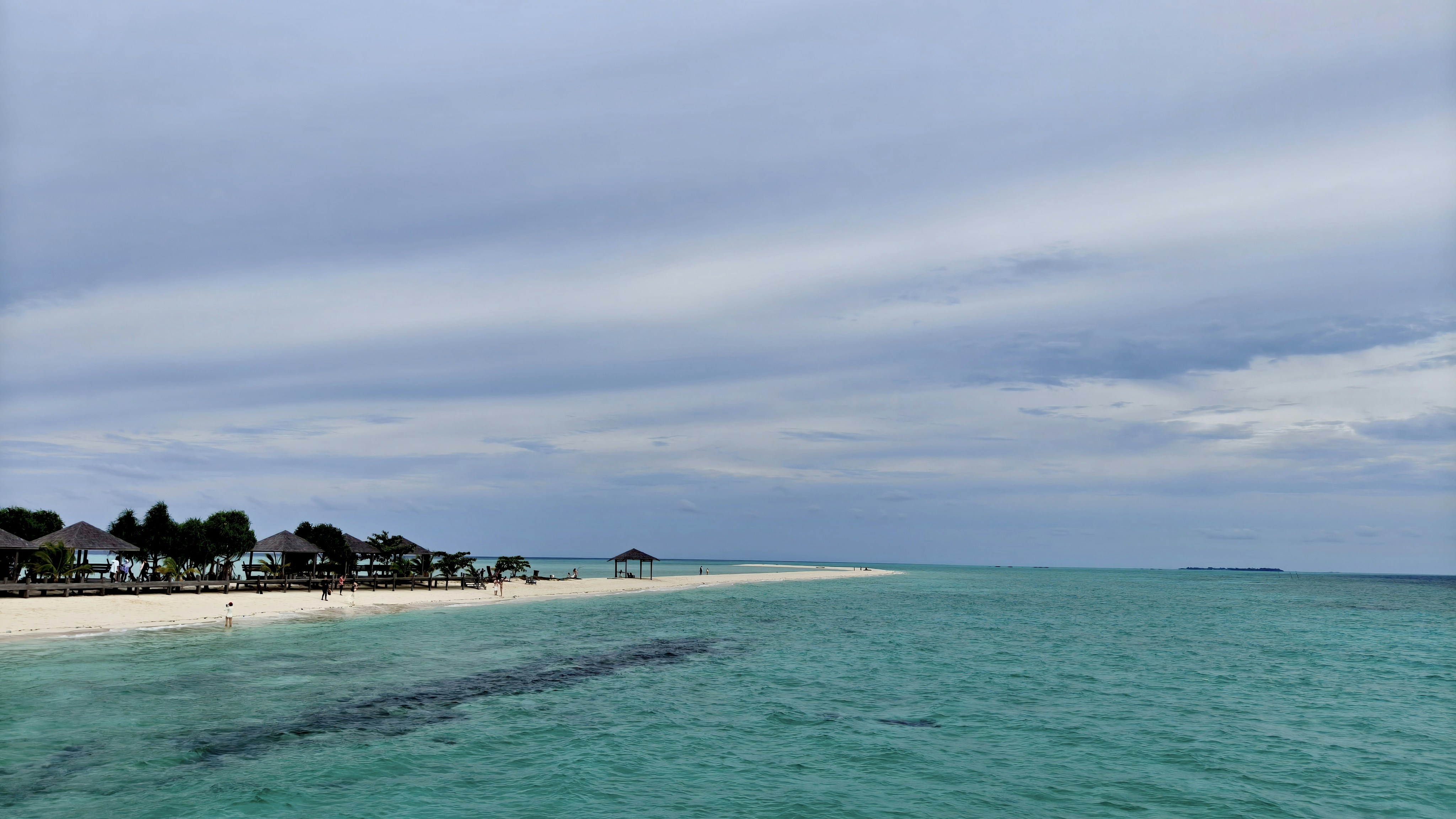 Turquoise ocean meets a white sand beach with houses.