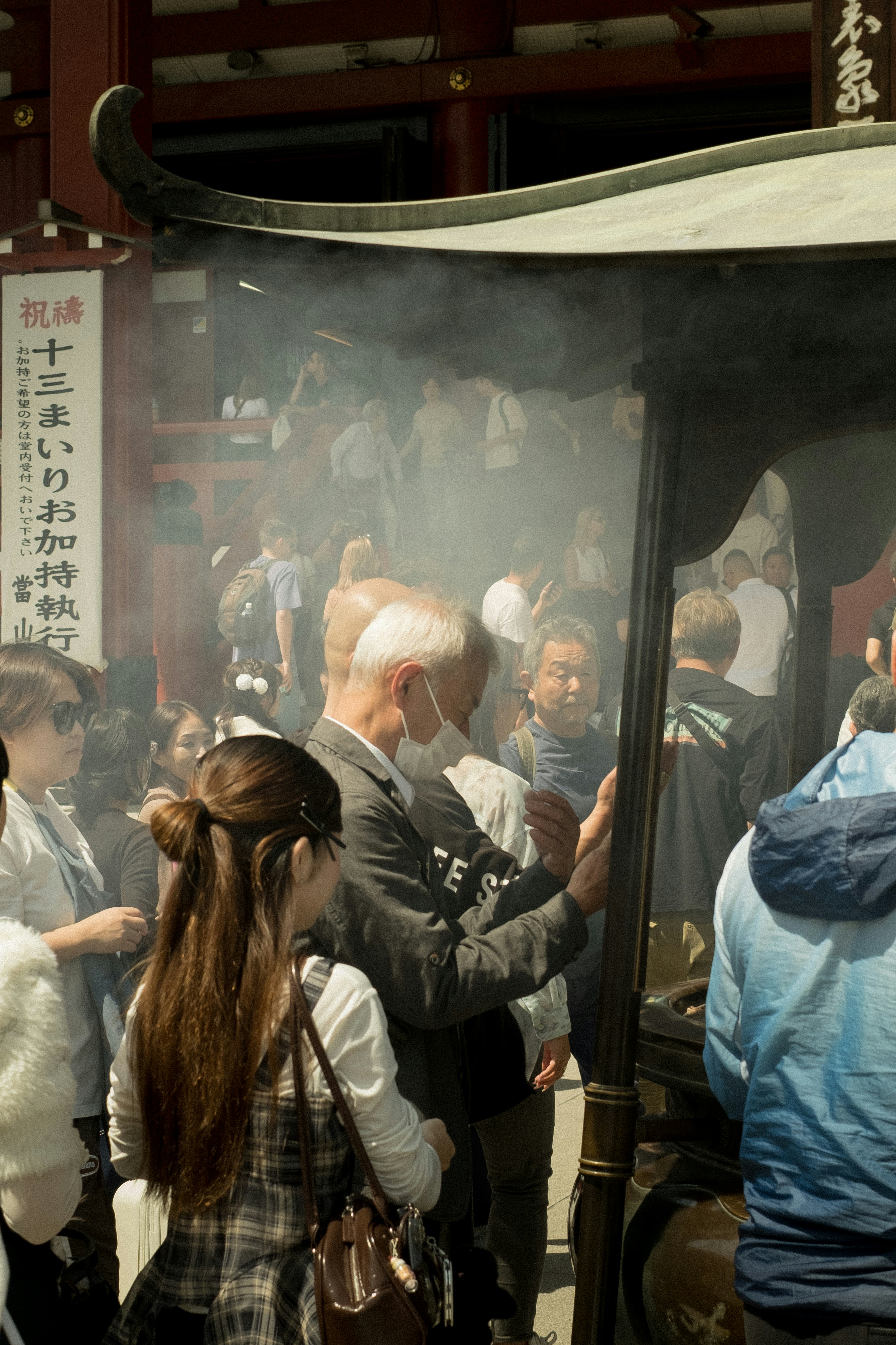 People gathered around an incense burner at a temple.