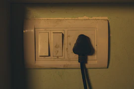 Electrical outlet with a black plug inserted.