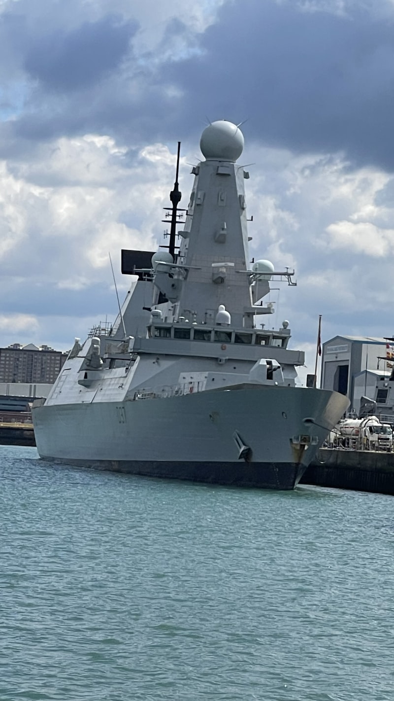A large grey warship docked in a harbour