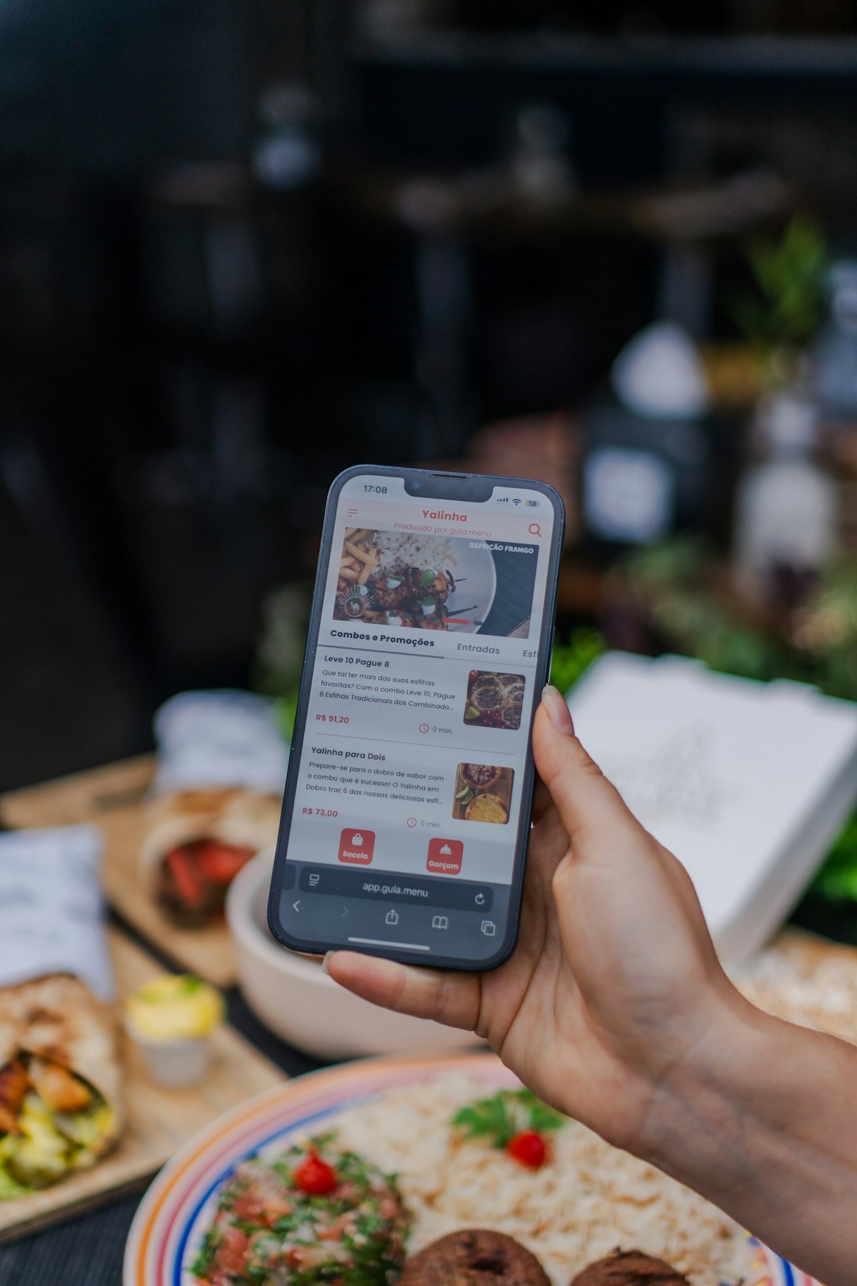 Mão segurando smartphone com aplicativo de pedido de comida aberto na tela